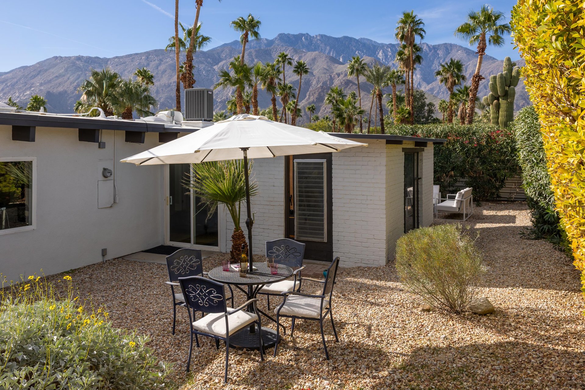 Midcentury modern vacation home surrounded by desert landscaping with stunning mountain views and private outdoor dining space.