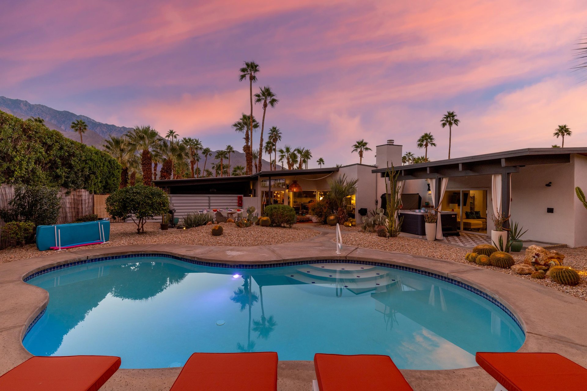 Midcentury modern desert retreat with private pool beneath stunning mountain vistas and vibrant sunset skies.