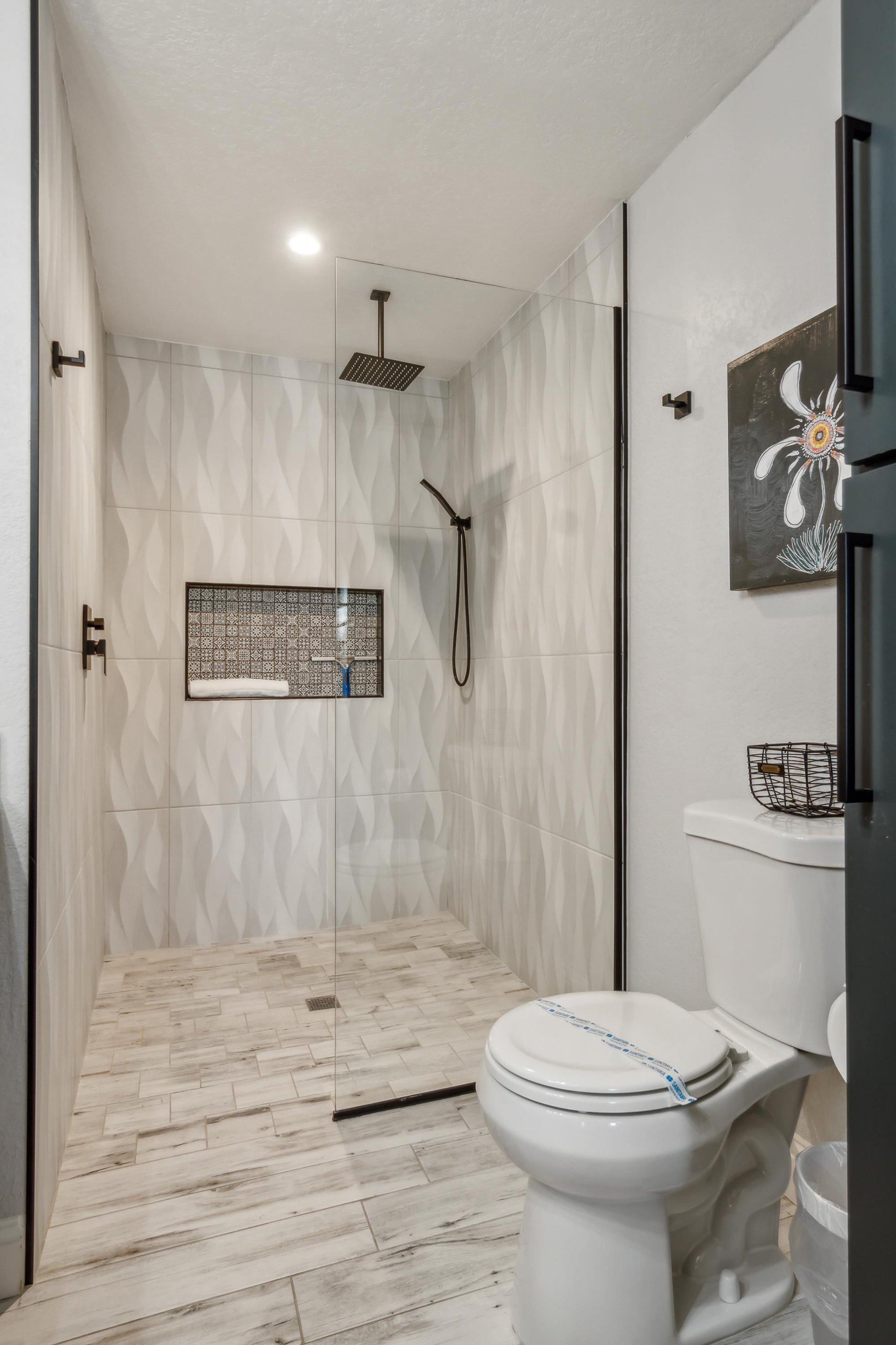 The master bathroom shower area is spacious, with elegant wavepatterned tiles that create a soothing and luxurious atmosphere. The shower is equipped with a rainfall showerhead, adding a touch of spalike comfort.