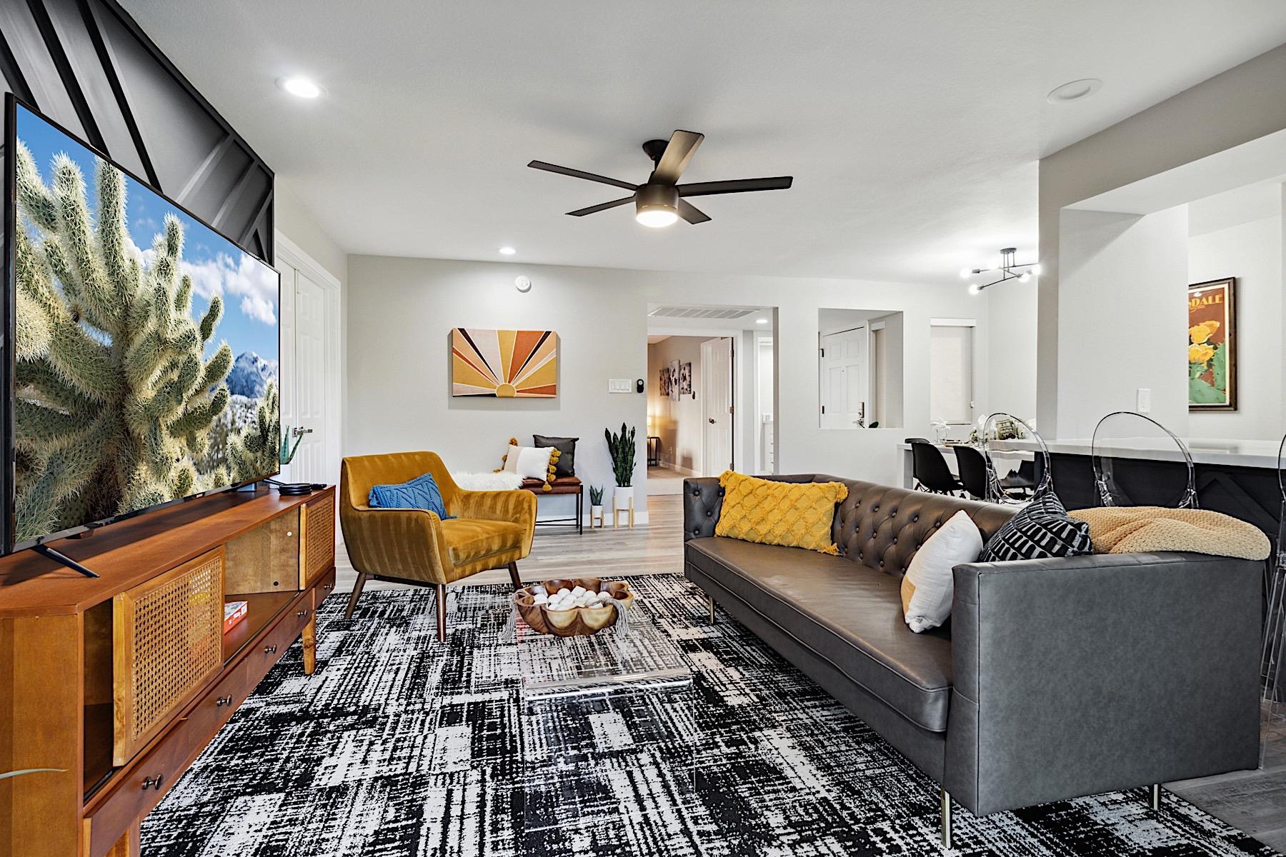 Living Room. Faux leather sofa, mustard sitting chair, clear coffee table, 65 Smart TV w Streaming