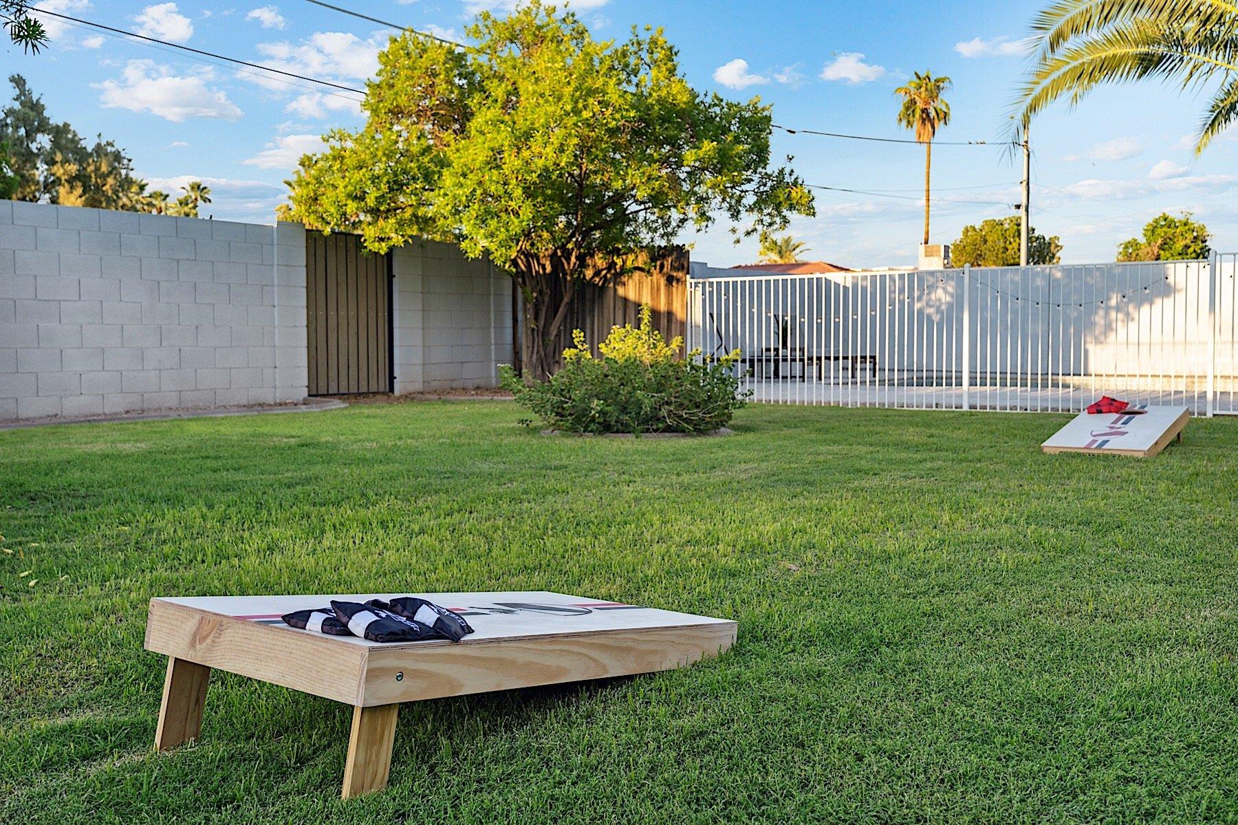 Big, grassy backyard with corn hole game