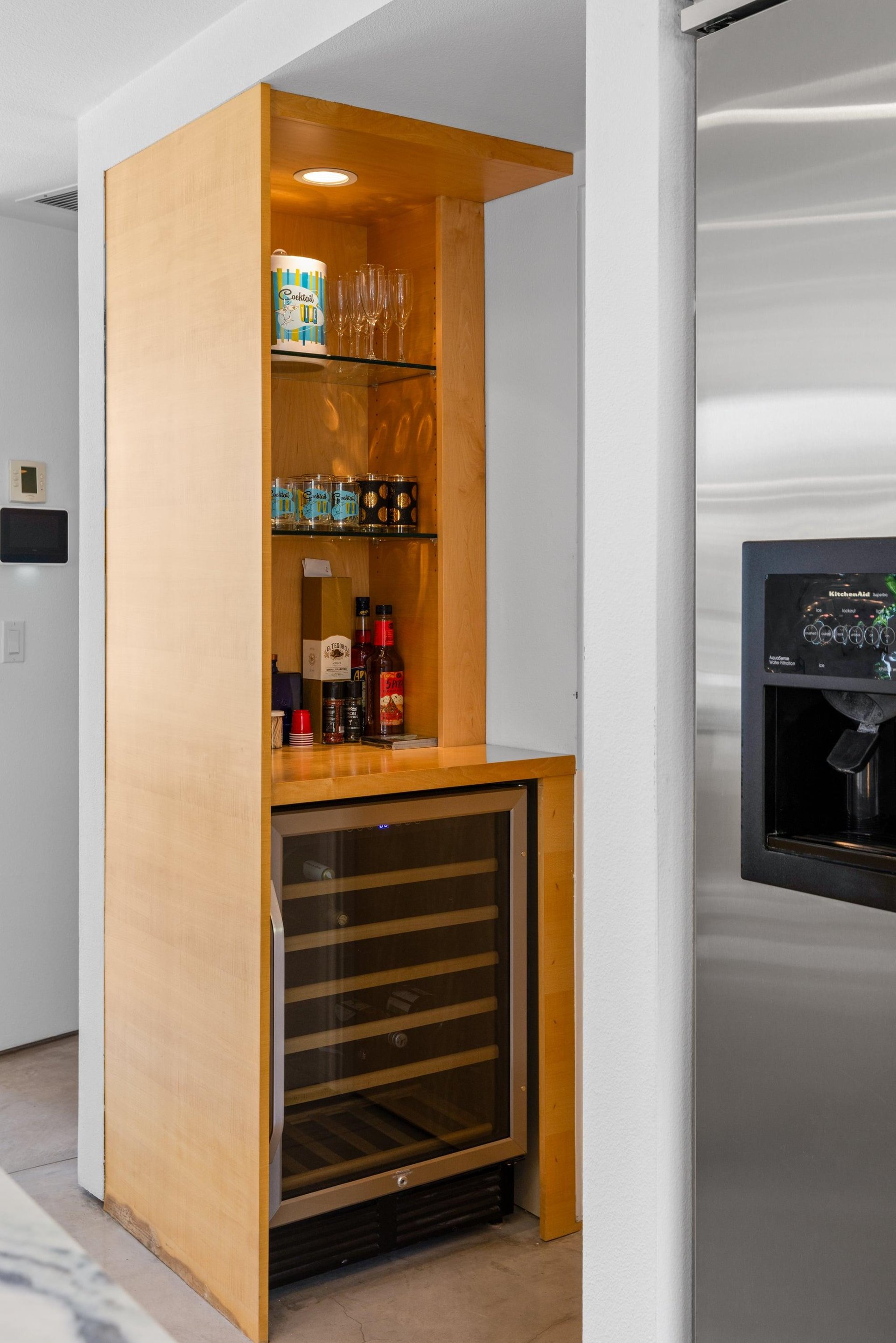 Modern chefs kitchen with a waterfall marble counter, kitchen island, stainlesssteel appliances, wine fridge, wet bar, and kitchen essentials.