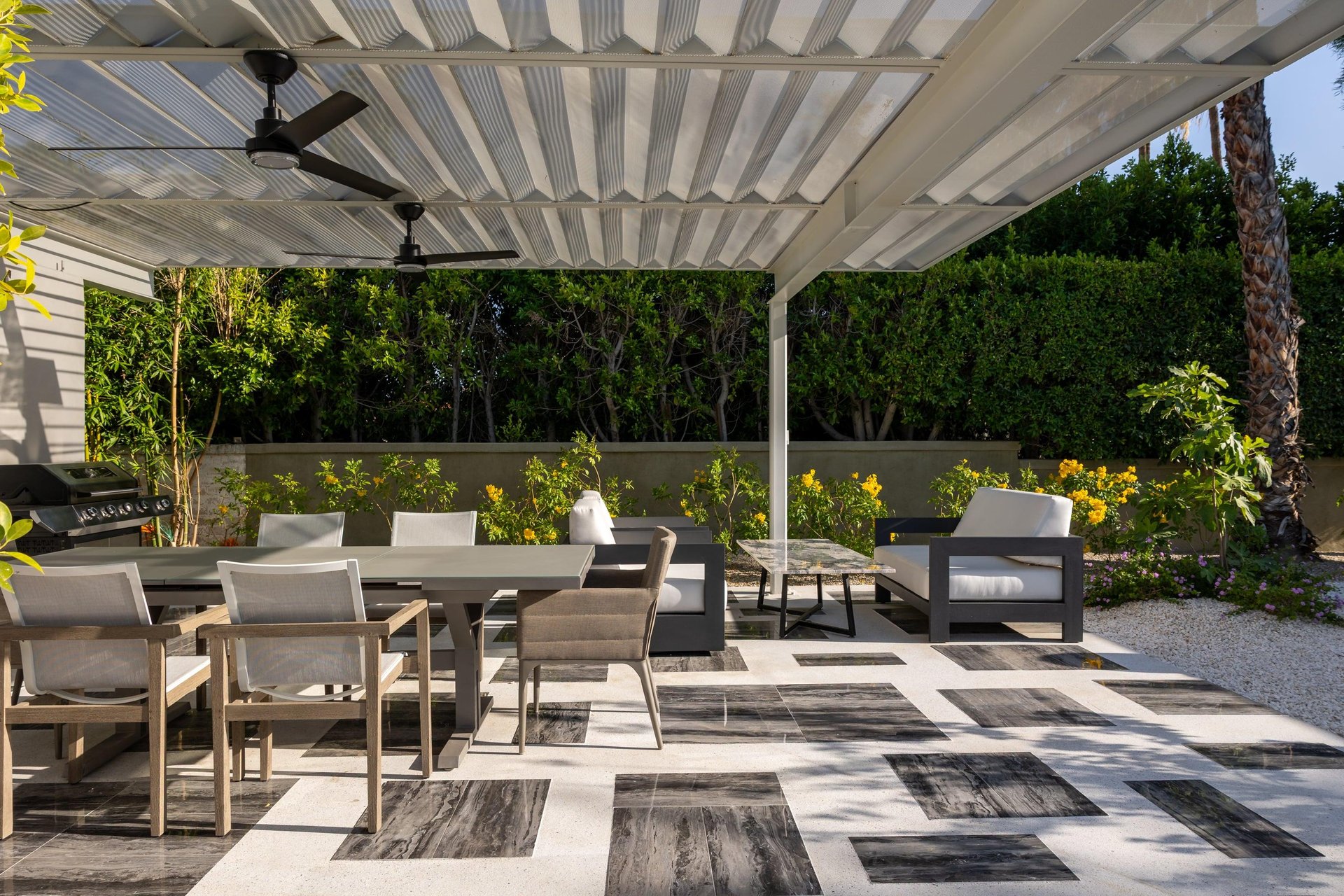 Outdoor dining area under pergola with fan, table, and seating for 6 guests. Additional seating area next to outdoor dining space.