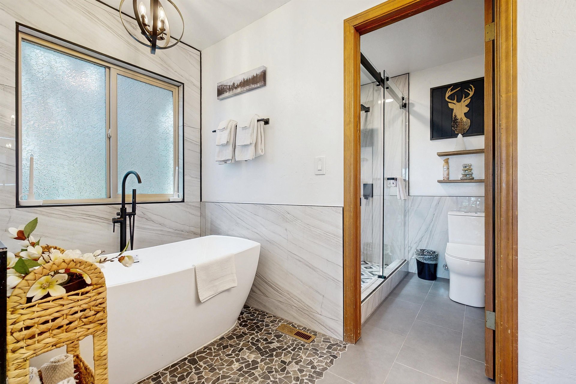 Ensuite bathroom with dual vanity sinks, modern fixtures, standalone tub, and walkin shower.