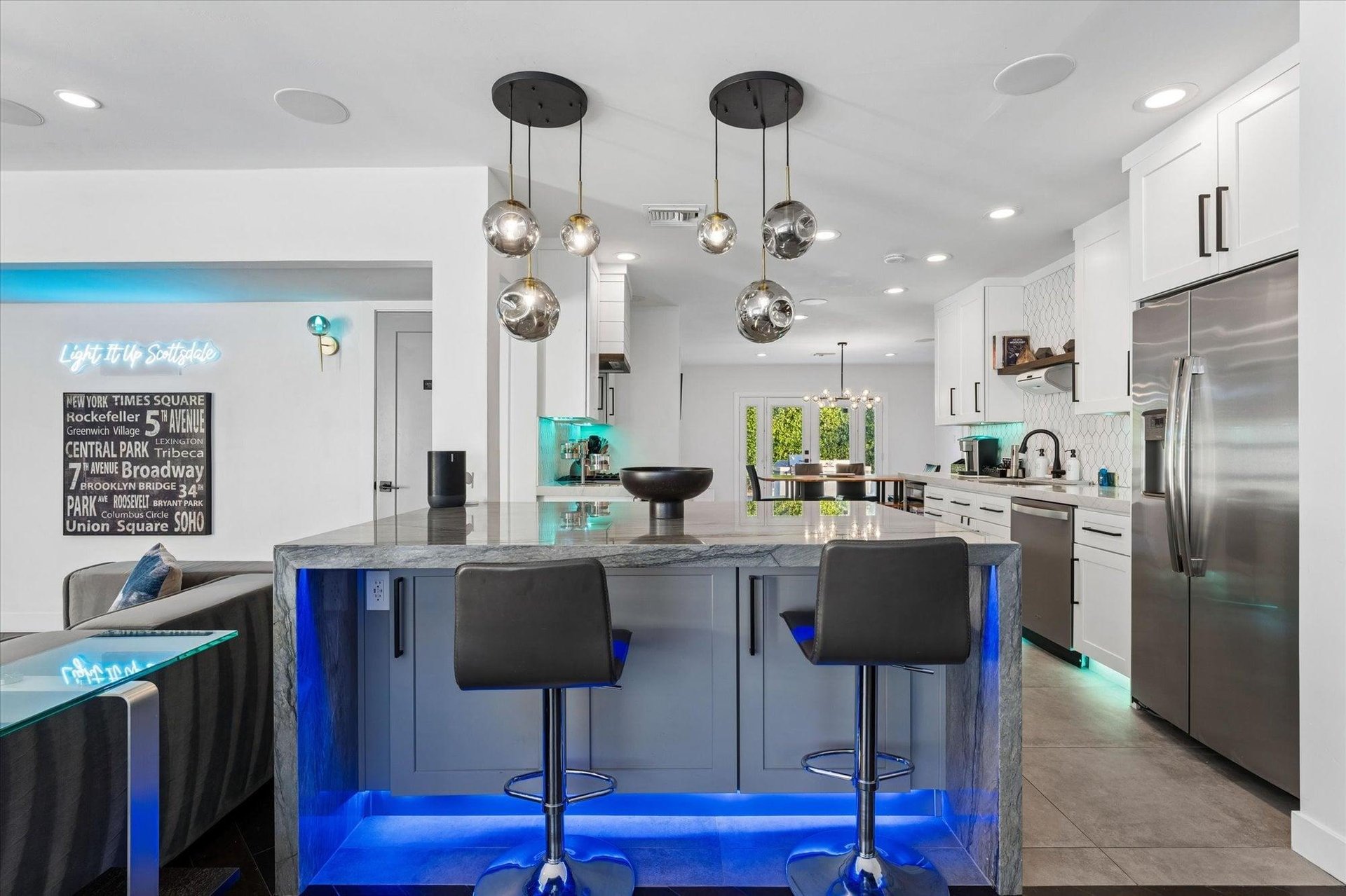 Fully equipped kitchen with island, counter seating, stainless steel appliances, and LED lighting.