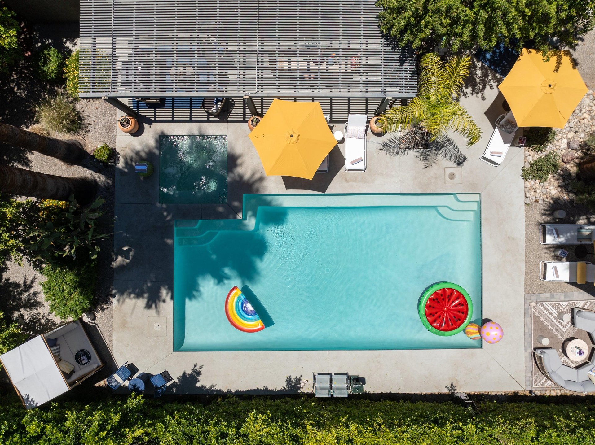 Entertainers backyard with outdoor seating, private pool and spa, sun loungers, cabana, and outdoor dining space.