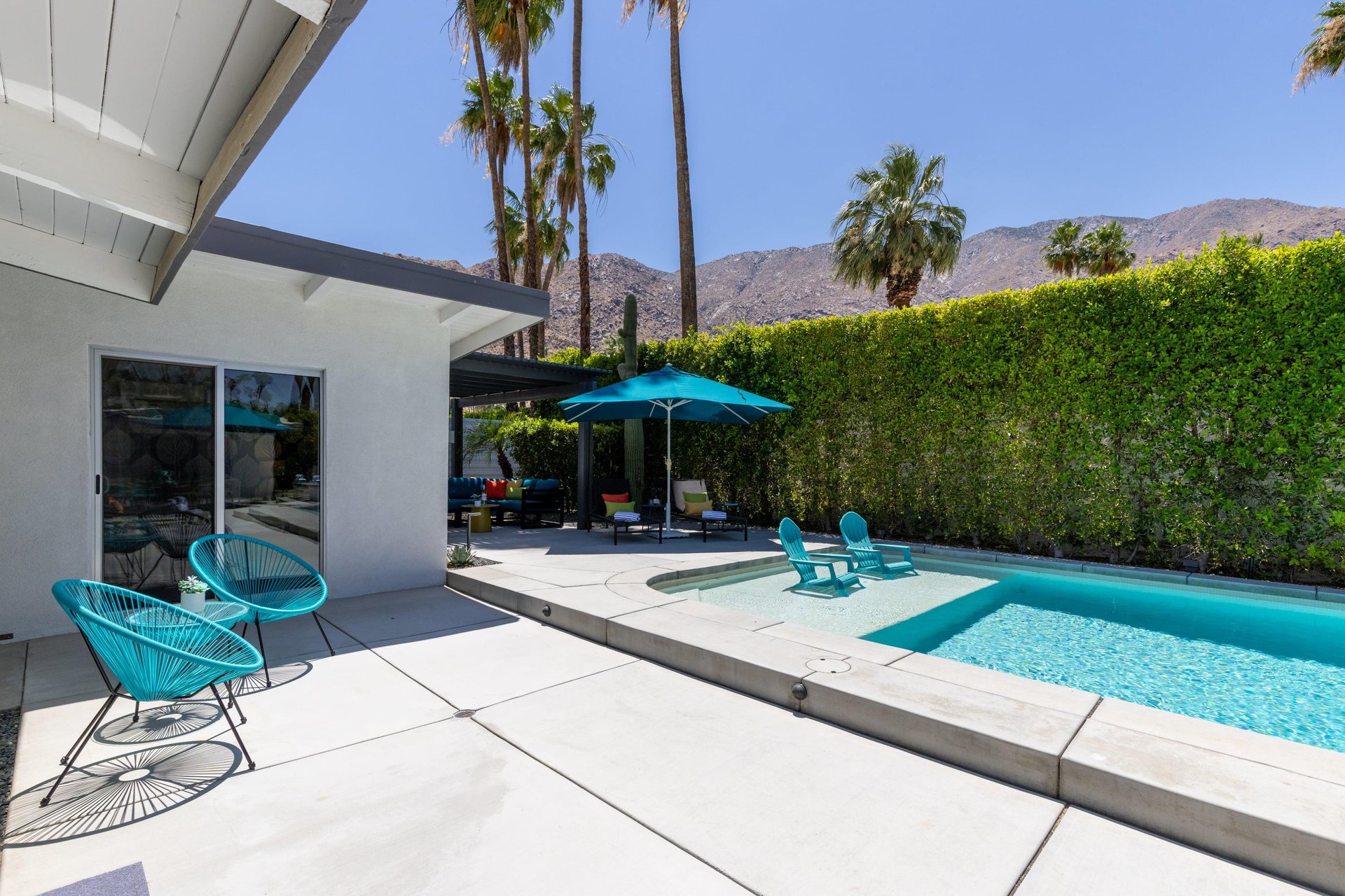 View of pergola with shaded outdoor seating and shallow end in pool.