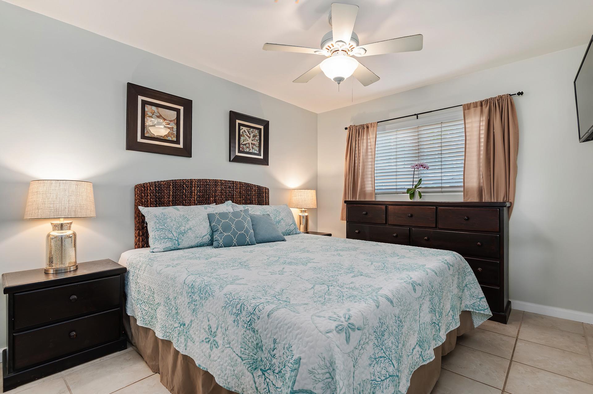 The primary bedroom has a large kingsize bed, dressers, and plenty of light.