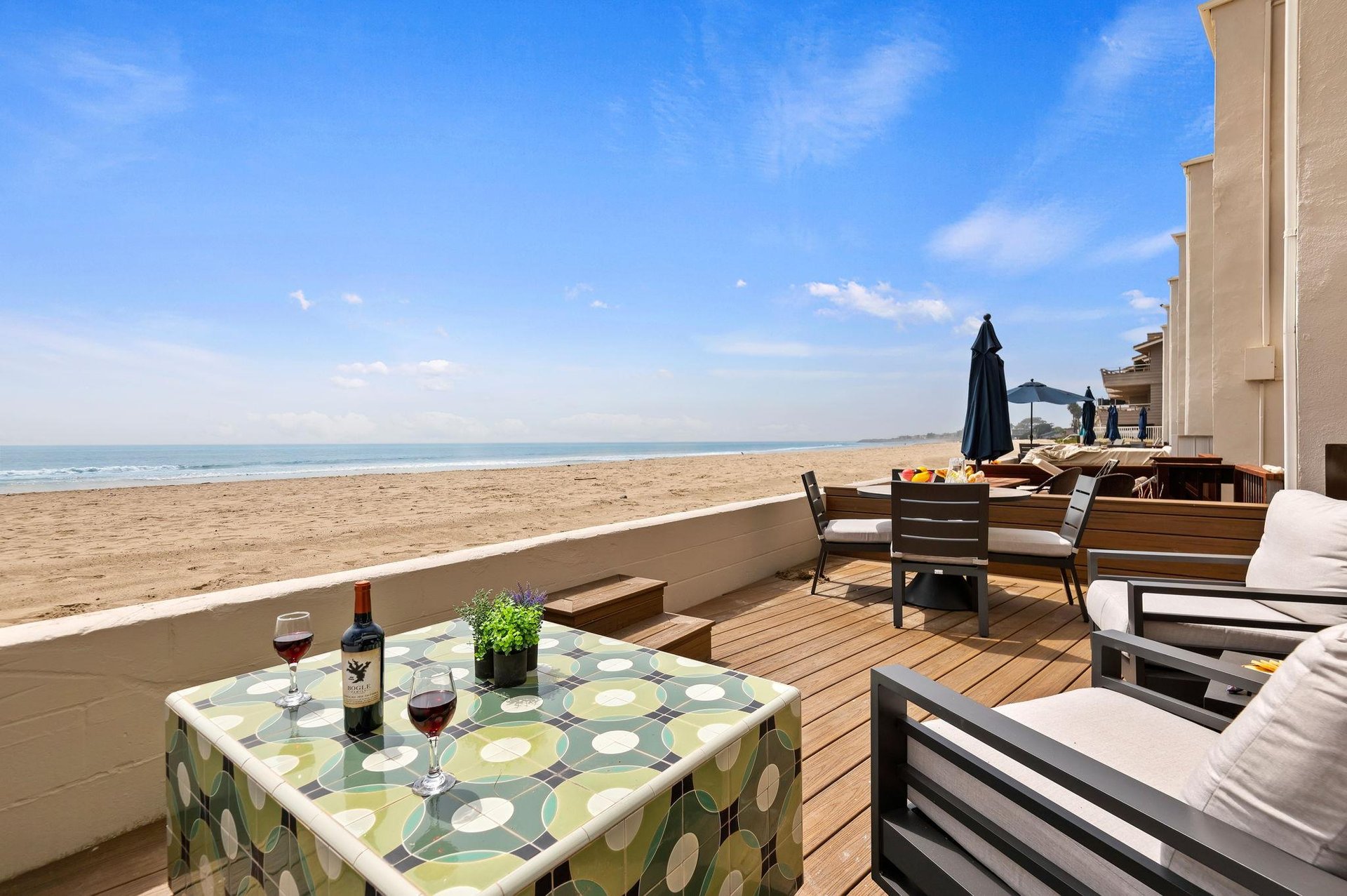 Incredible beach Front deck with comfortable couch, chairs, and dining area.