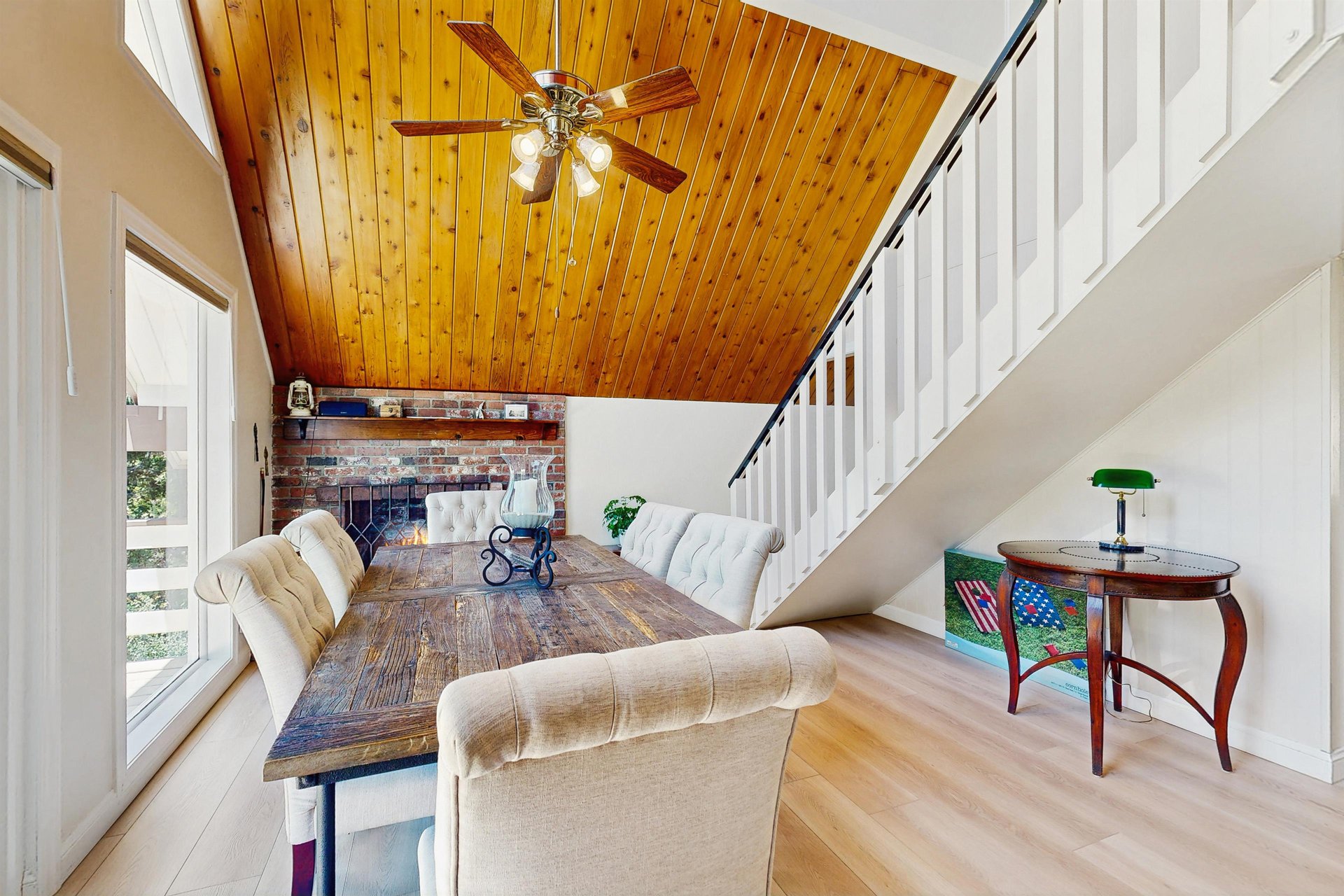 Dining area with vaulted ceilings, large windows, deck access, fireplace, and table and chairs for 6 guests.