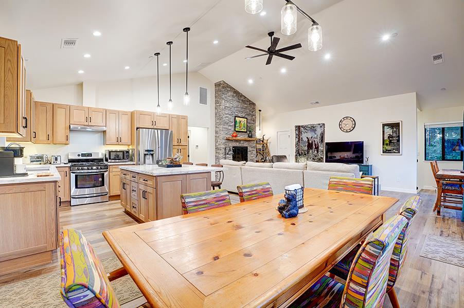 Dining area with table and chairs for 6 guests. Kitchen with stainless steel appliances, kitchen island with seating, and cooking essentials.