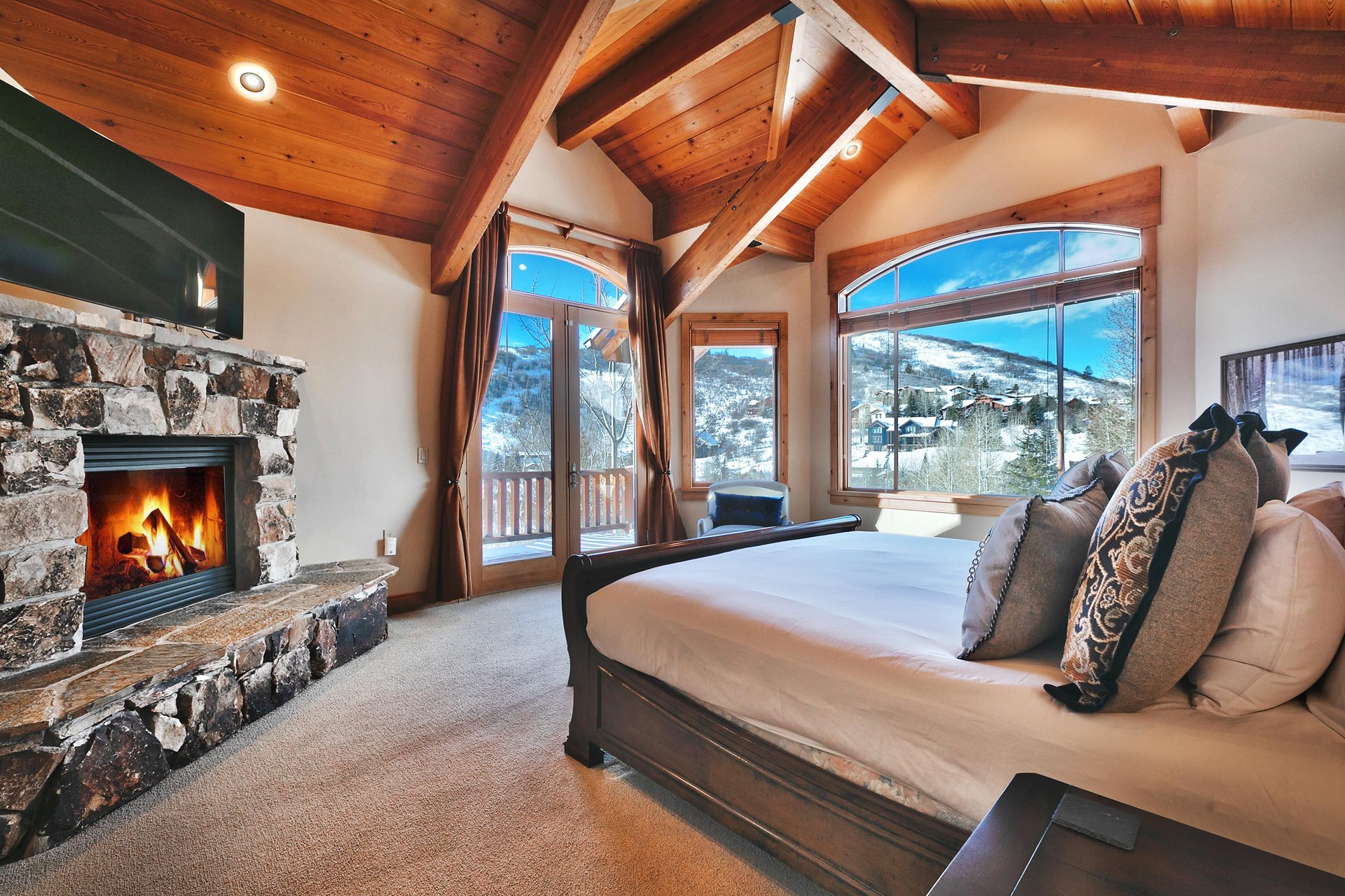 King bed, private patio and large picture windows, gas fireplace in flagstone surround, vaulted wood beam ceiling.