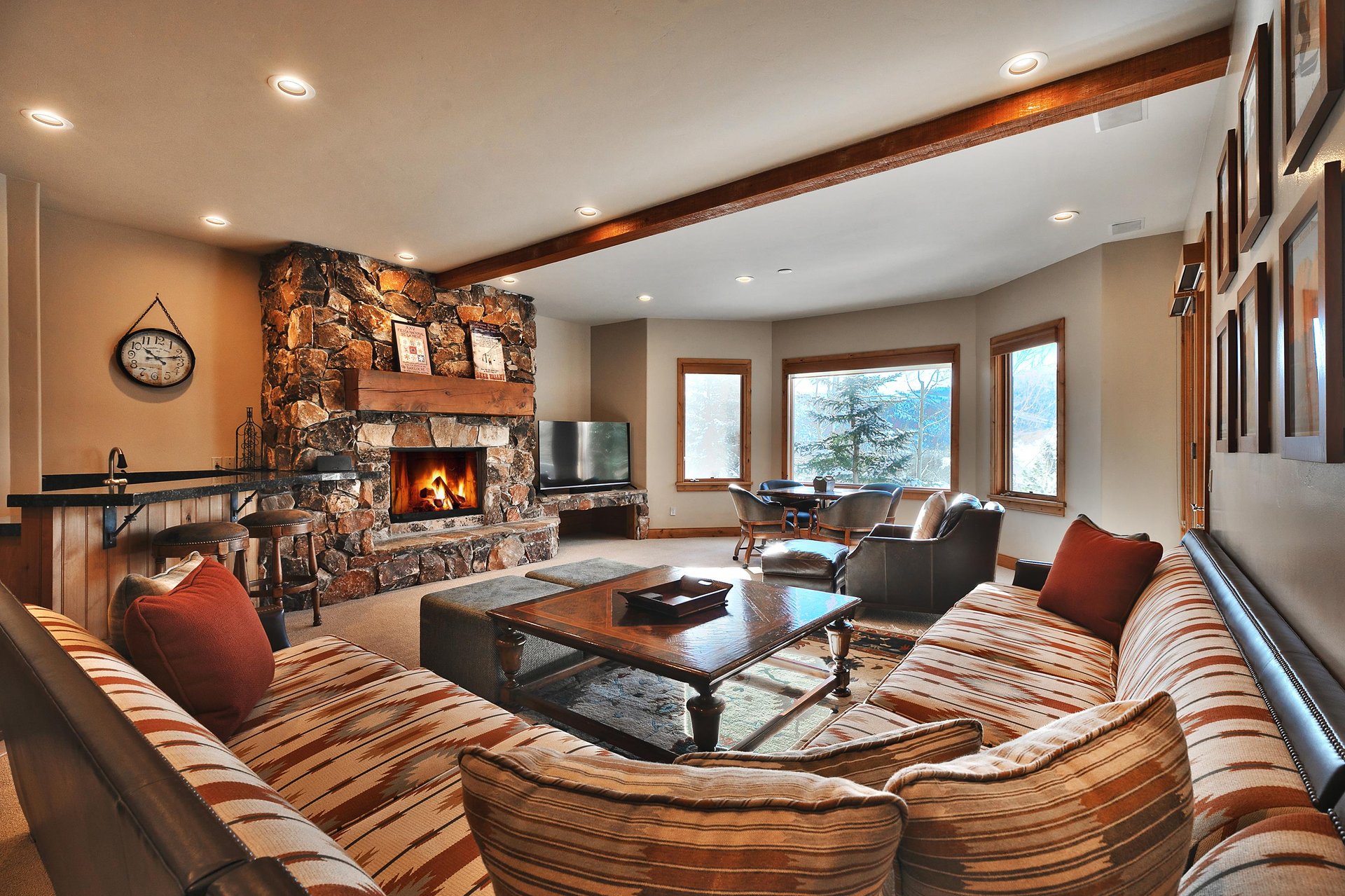 Second living room with expansive southwestern upholstered sectional, gas burning fireplace with stone surround, and TV.