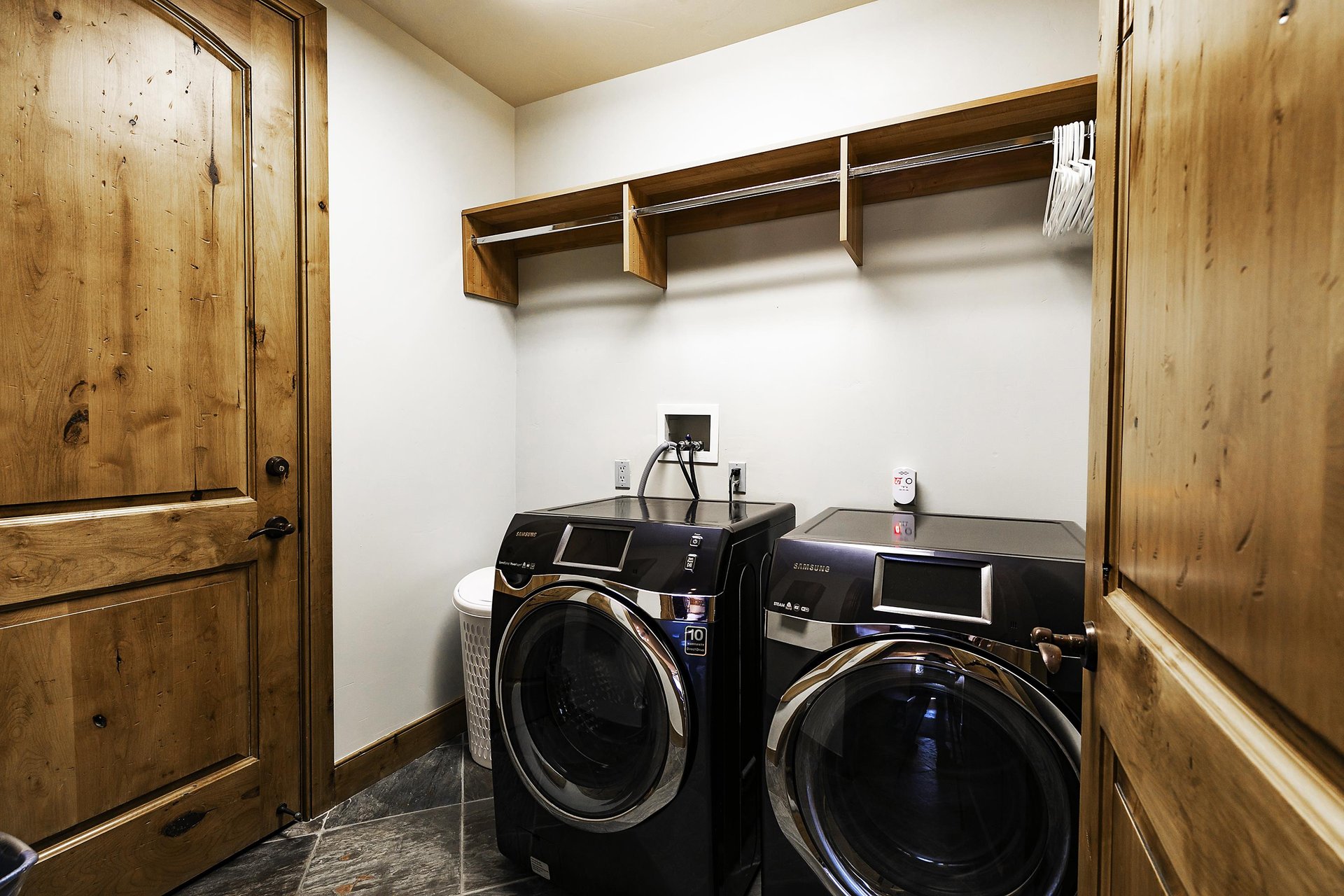 First set of front loading washer and dryer in a black color with storage above there is a second set on a different floor.