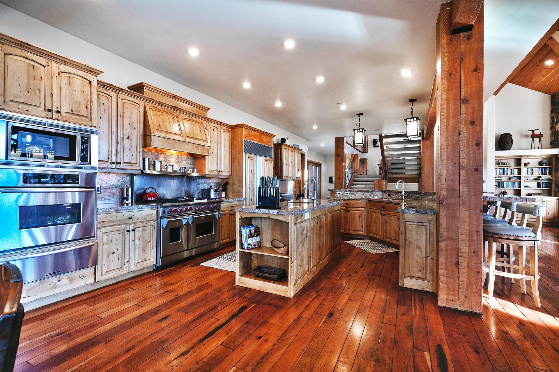 A chefs kitchen with two kitchen islands, wooden cabinetry, granite countertops, and stainless steel state of the art appliances.