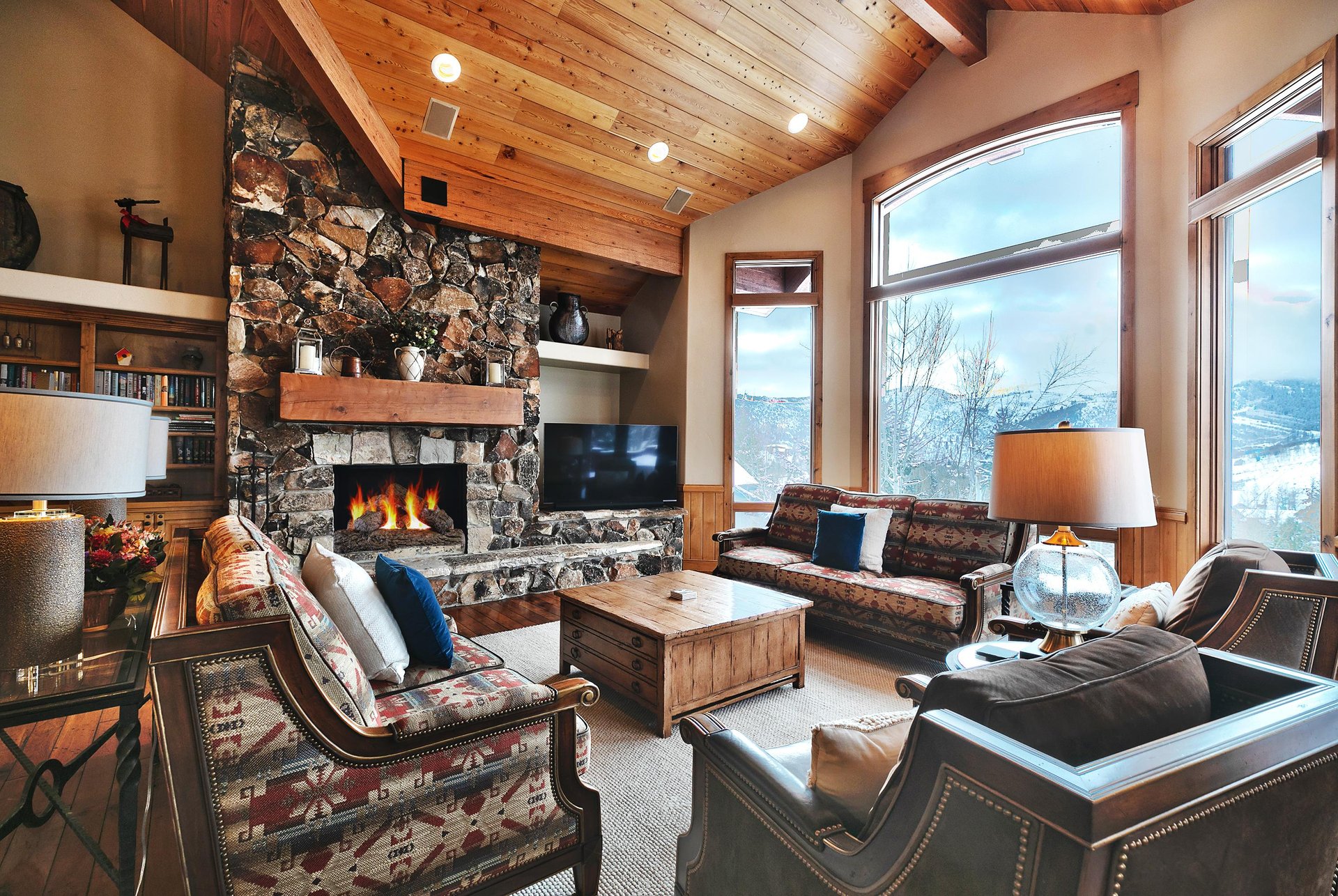 Floor to ceiling stone hearth with wood burning fireplace in the living room and 2 comfortable couches and club chairs.