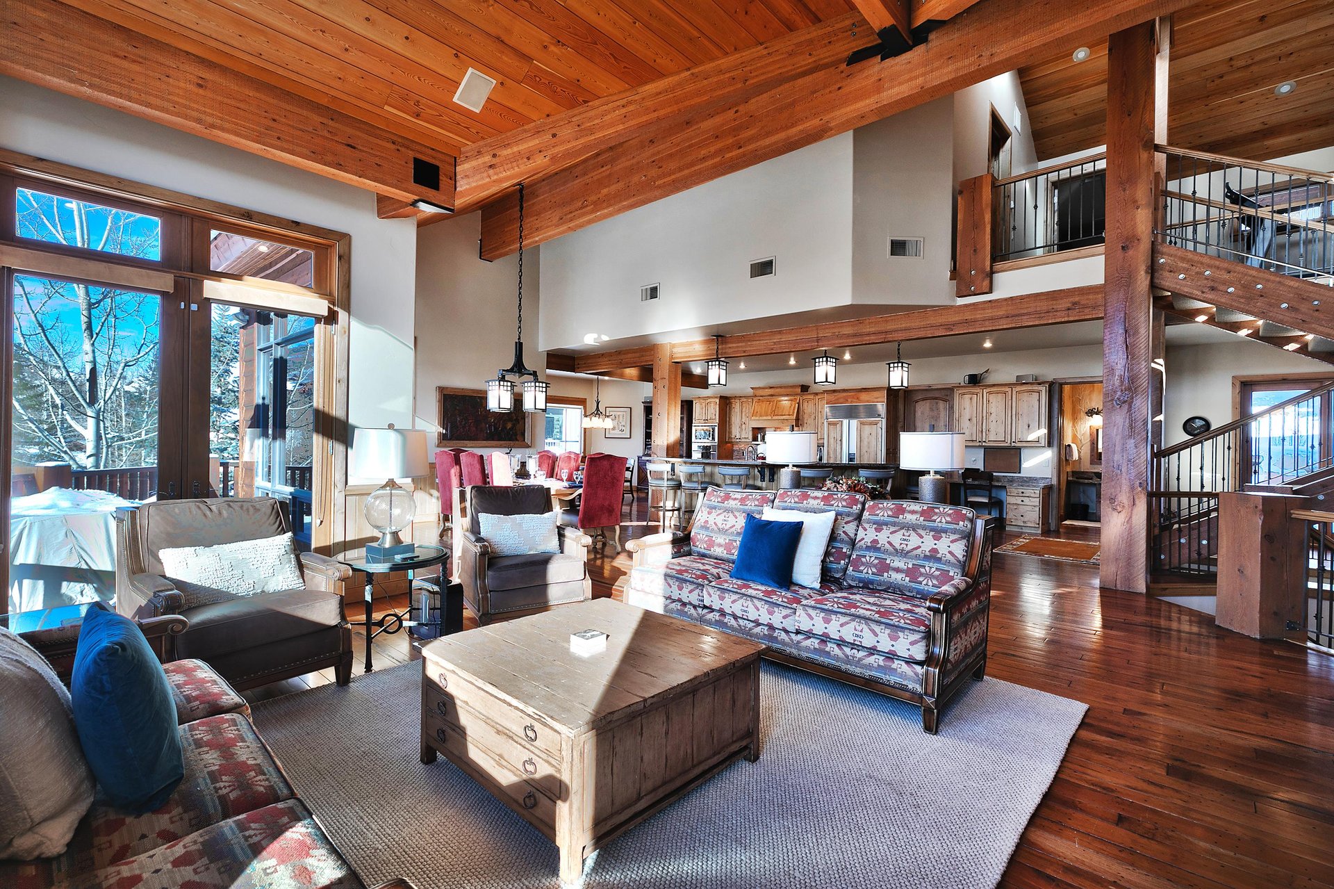 Solid wood coffee table in the living room with upholstered couches, 2 chairs, cream walls, and hard wood floors and ceiling.