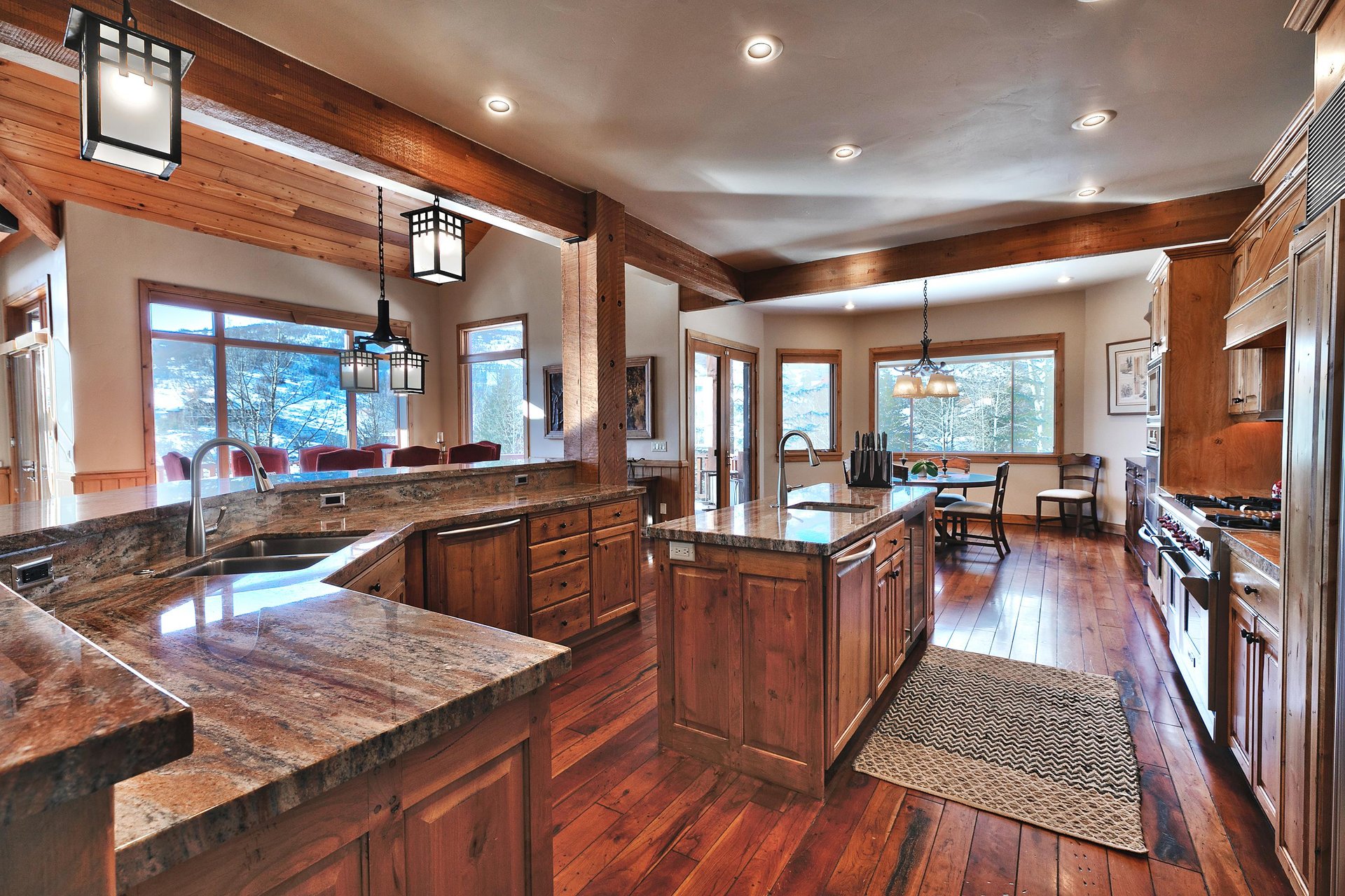 Two kitchen islandsone wrap around and one center island, both have sinks, medium wood cabinets, and granite countertops.