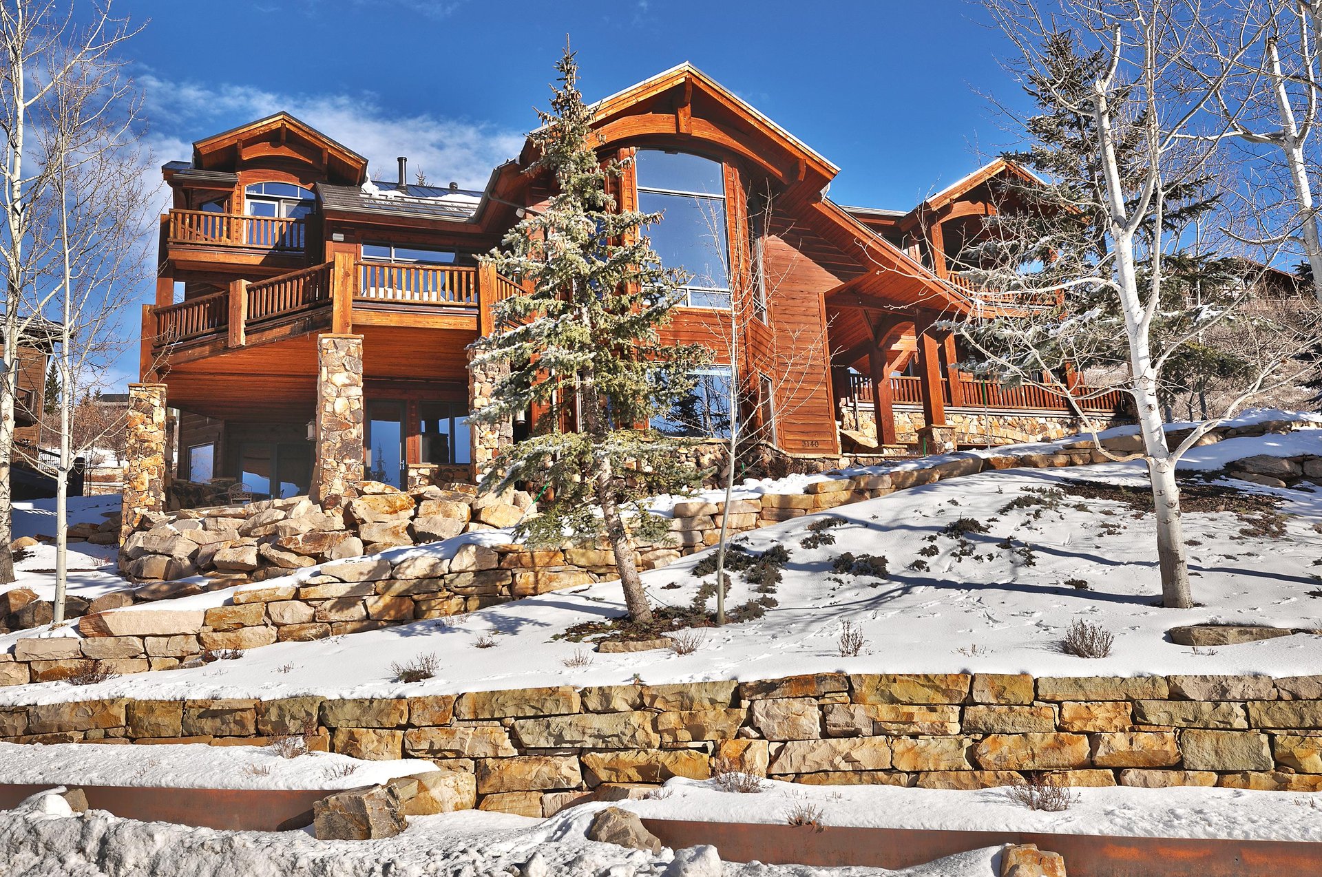 The wood and stone sided Thistle Home exterior after a fresh snow on a sunny winter day.