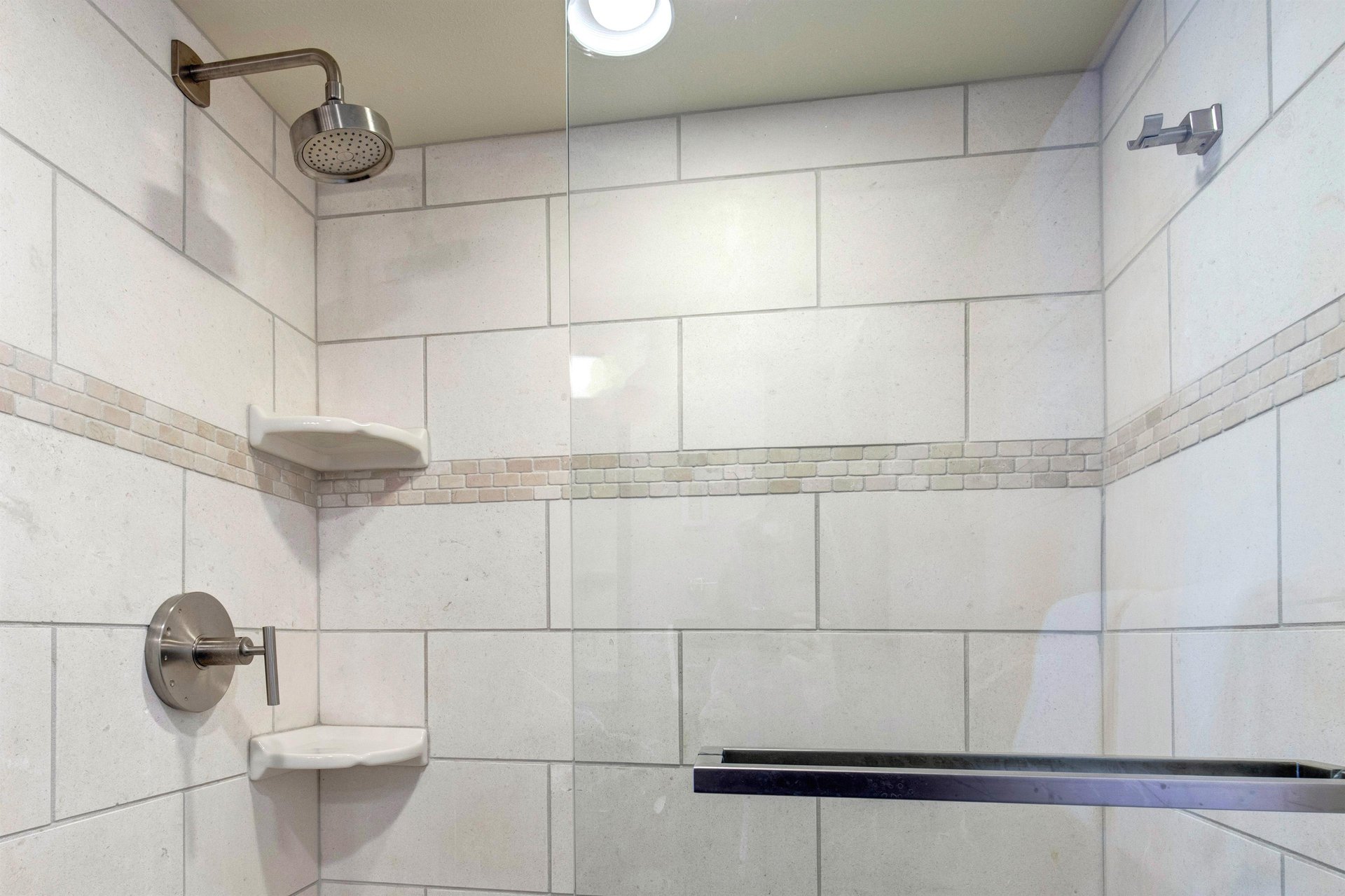 The bathroom with a walkin tiled shower.