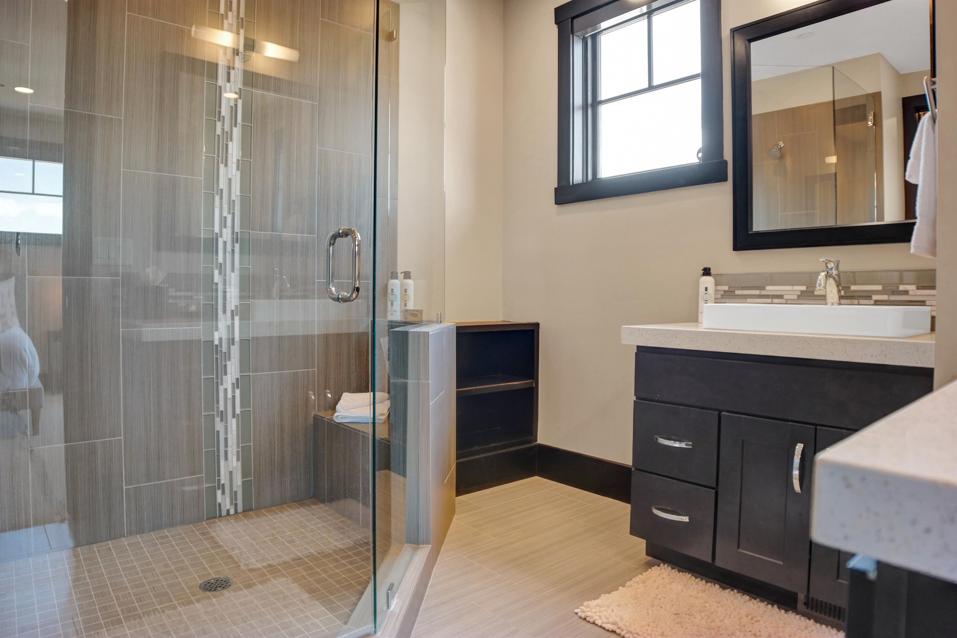 En suite bathroom with walk in grey tiled shower with glass surround