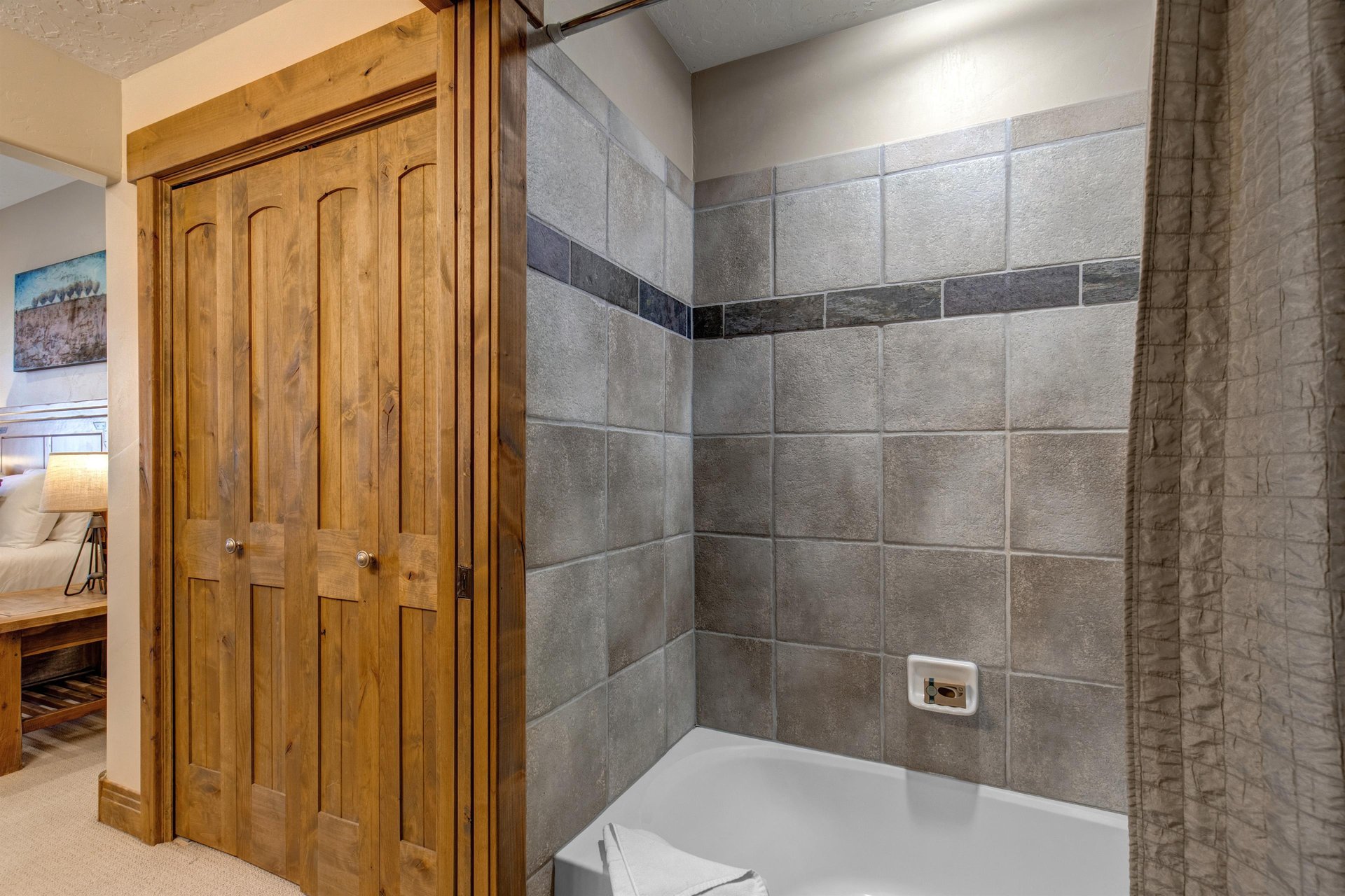 Step into your private bathroom featuring elegant gray tile work and a deep soaking tub where you can unwind after mountain adventures.