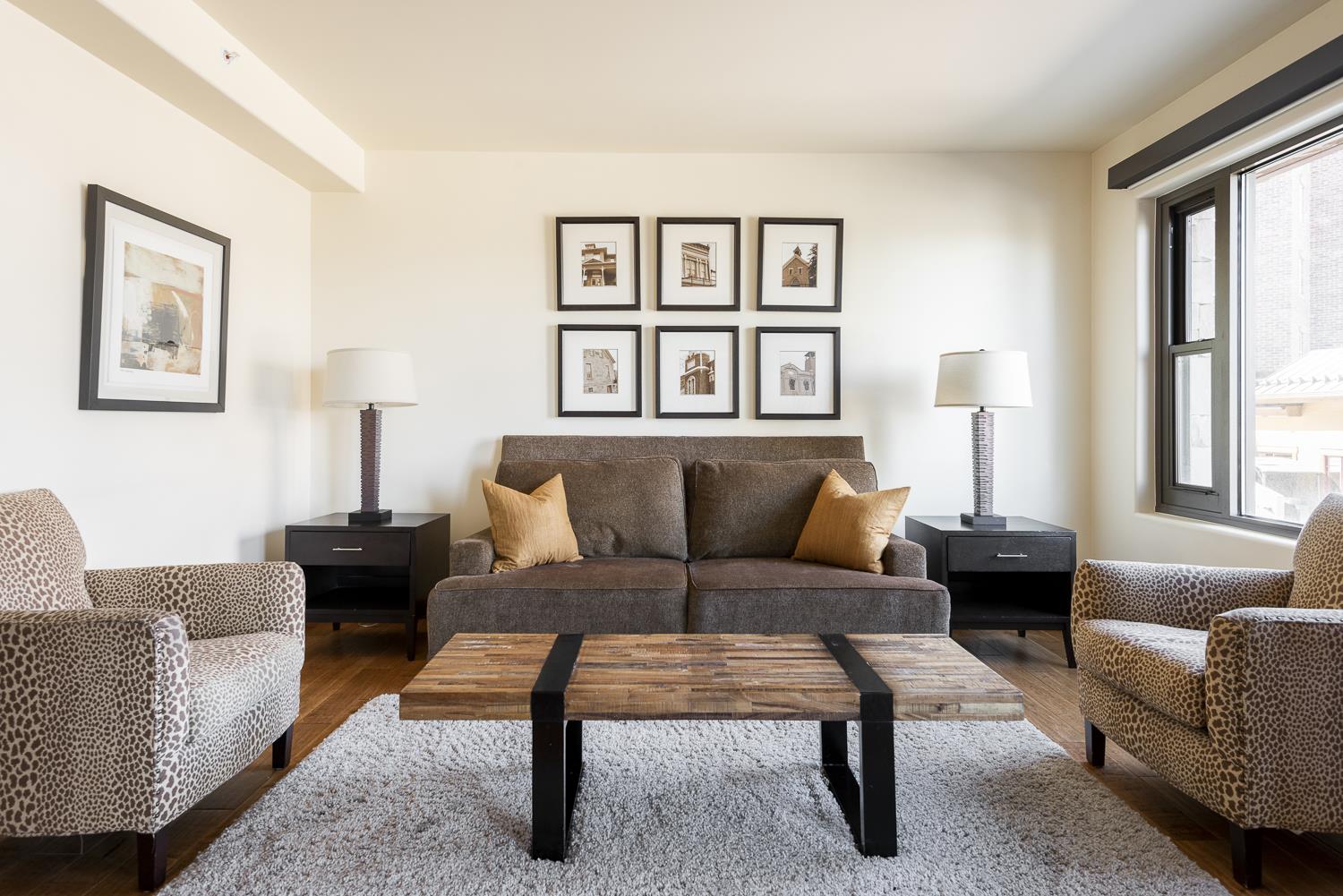 Bright living room with modern wod and metal coffee table, earth tone furnishings with accent cheetah print lounge chairs