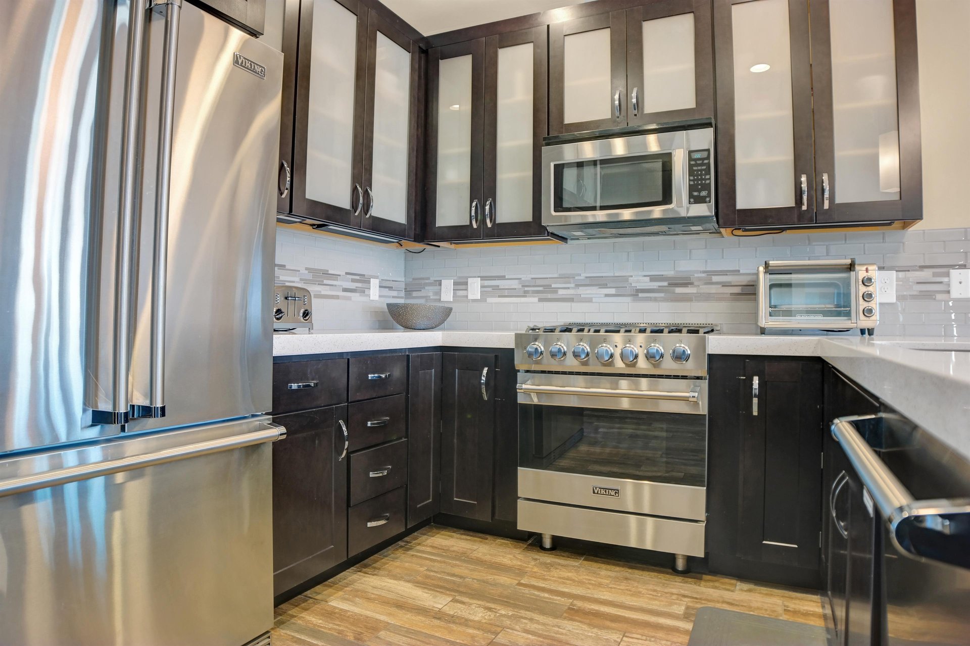 The kitchen with stainless steel Viking appliances, dark wood cabinets and neutral tiled backsplash.