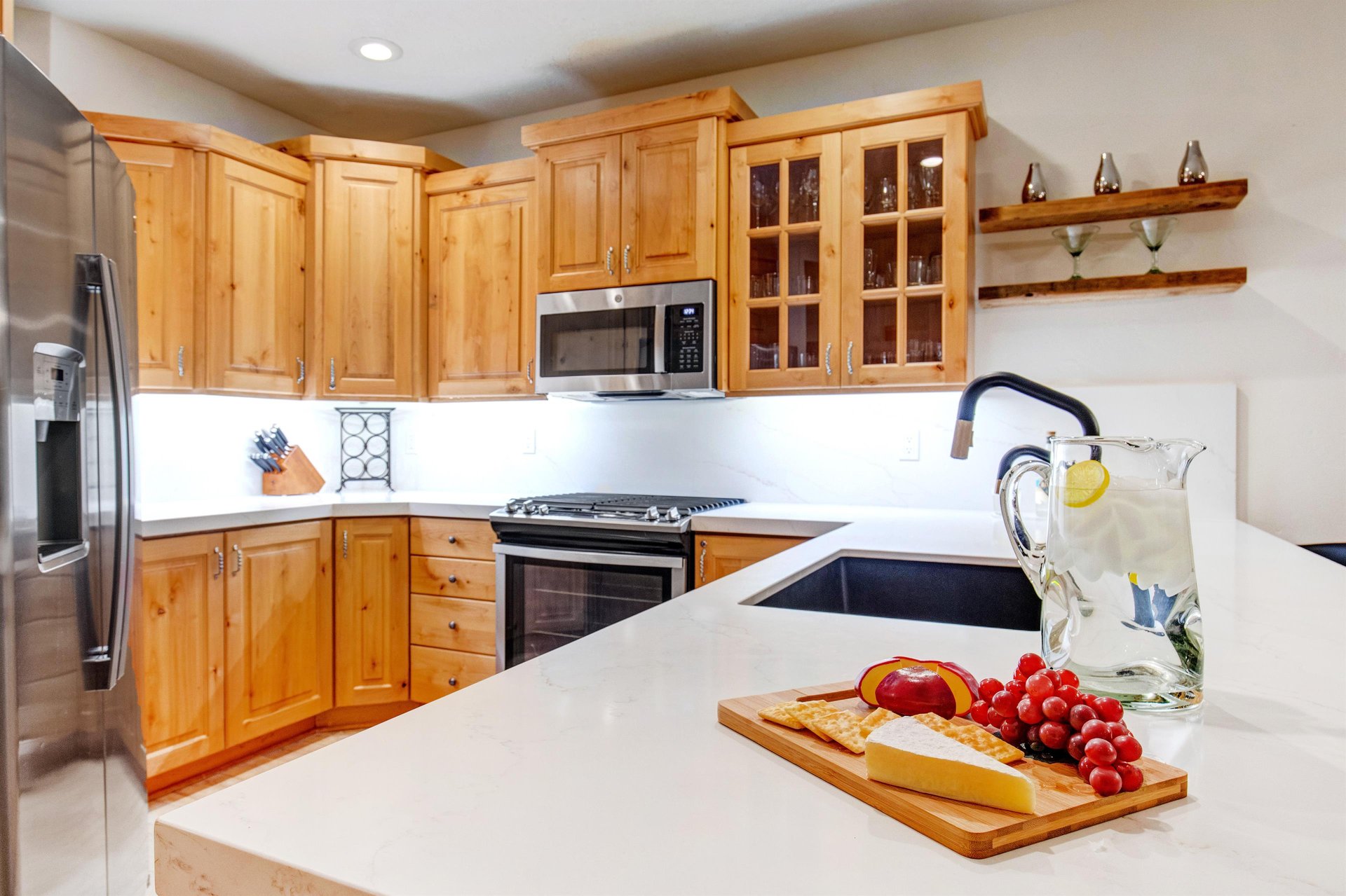 This Park City Lodging vacation rental offers a fullyequipped kitchen with white countertops and warm wood cabinetry.