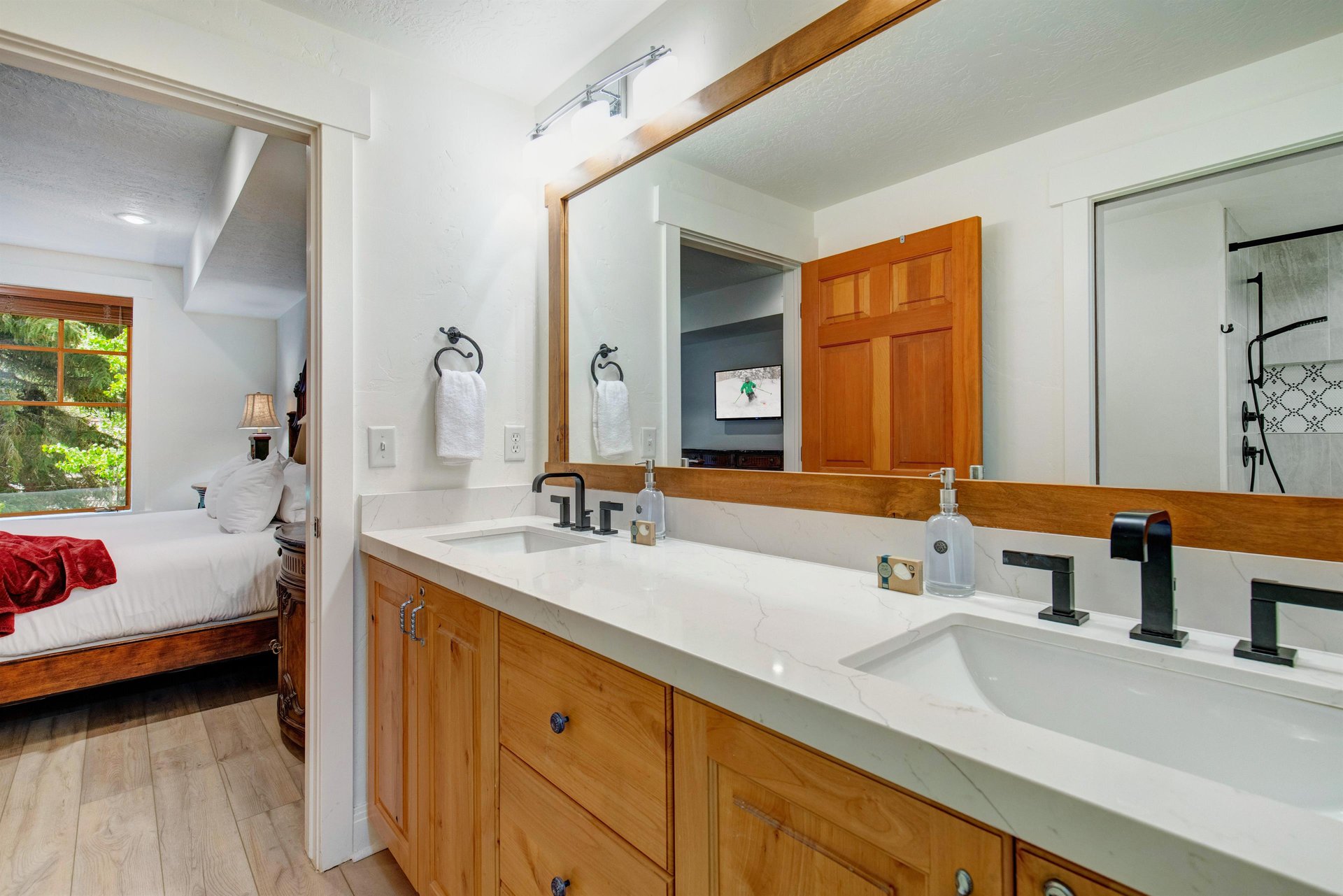 Your ensuite bathroom features double sinks, warm wood cabinetry, and a sleek marble countertop.
