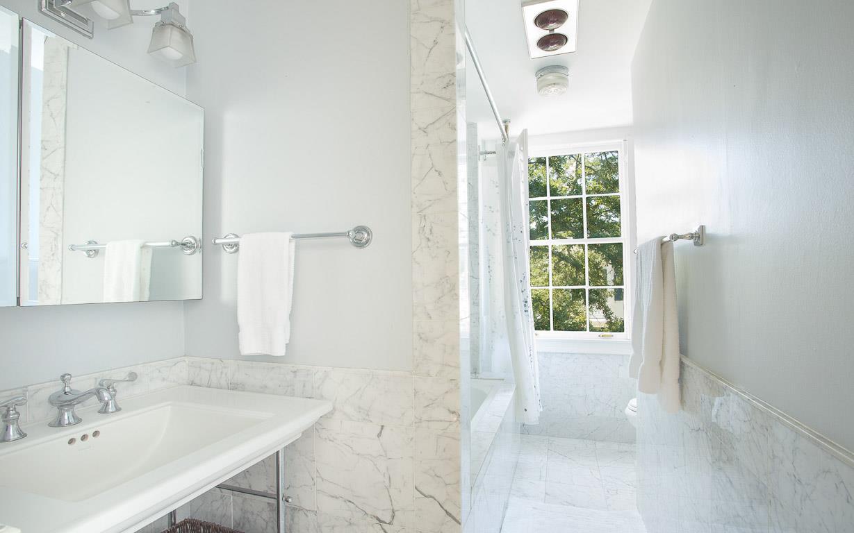 The primary bath embodies luxury with Carrera marble and fluffy white towels.