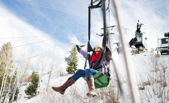Guest riding a zipline above snowy terrain near Park City ski in ski out vacation rentals