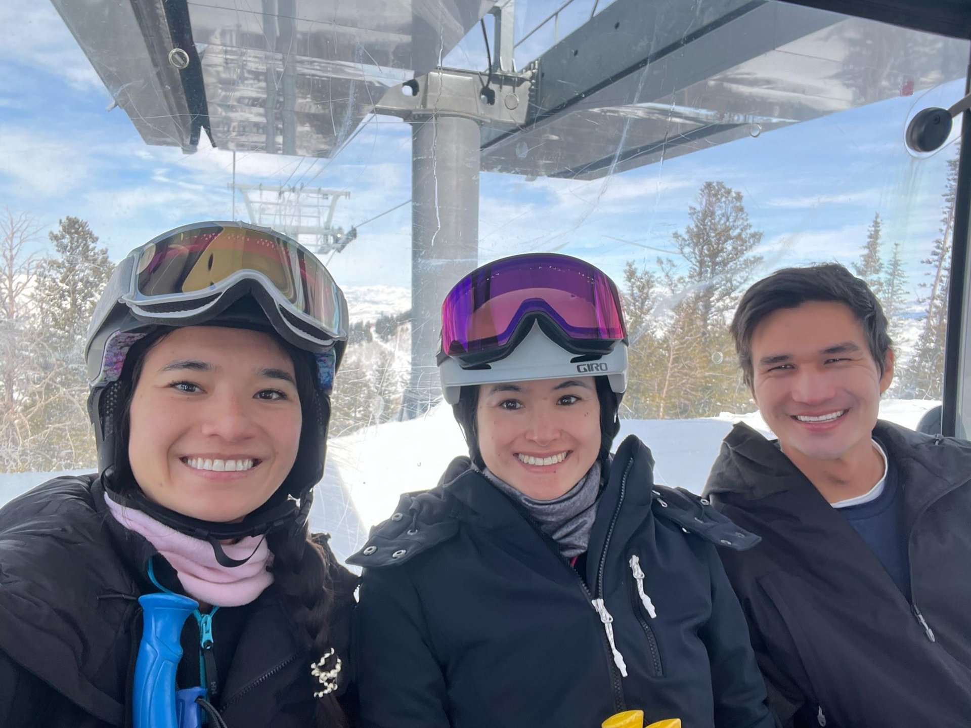 Friends enjoying a ski lift ride on a sunny winter day in Park City, Utah Three smiling skiers riding a chairlift on a sunny winter day in Park City, Utah with snowcovered mountains in the background
