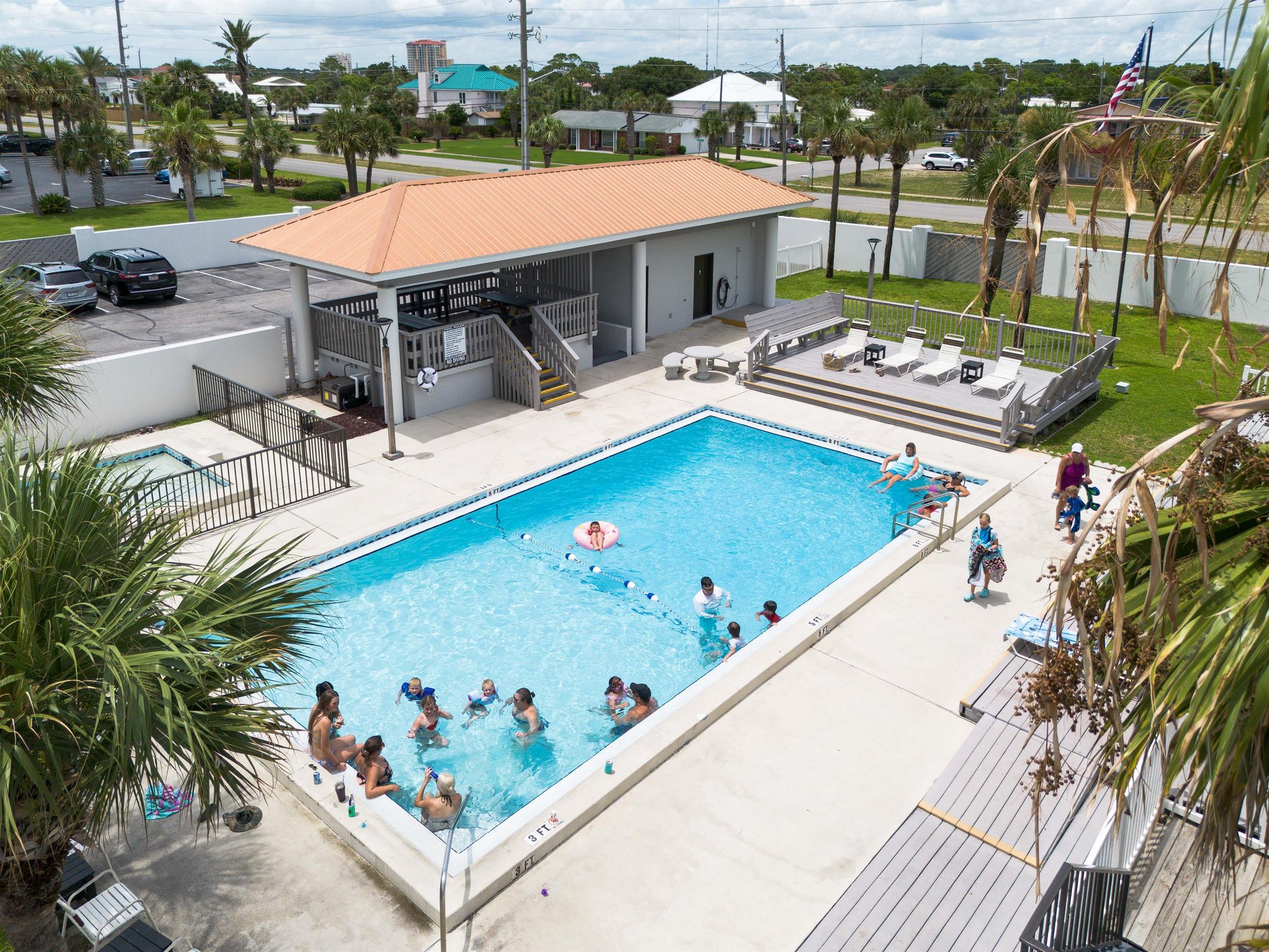 The pool area is located on the front of the property and is gated for safety. It is a large area with a separate kiddie pool, a deck for sunbathing, and a raised gazebo area with a couple of picnic t