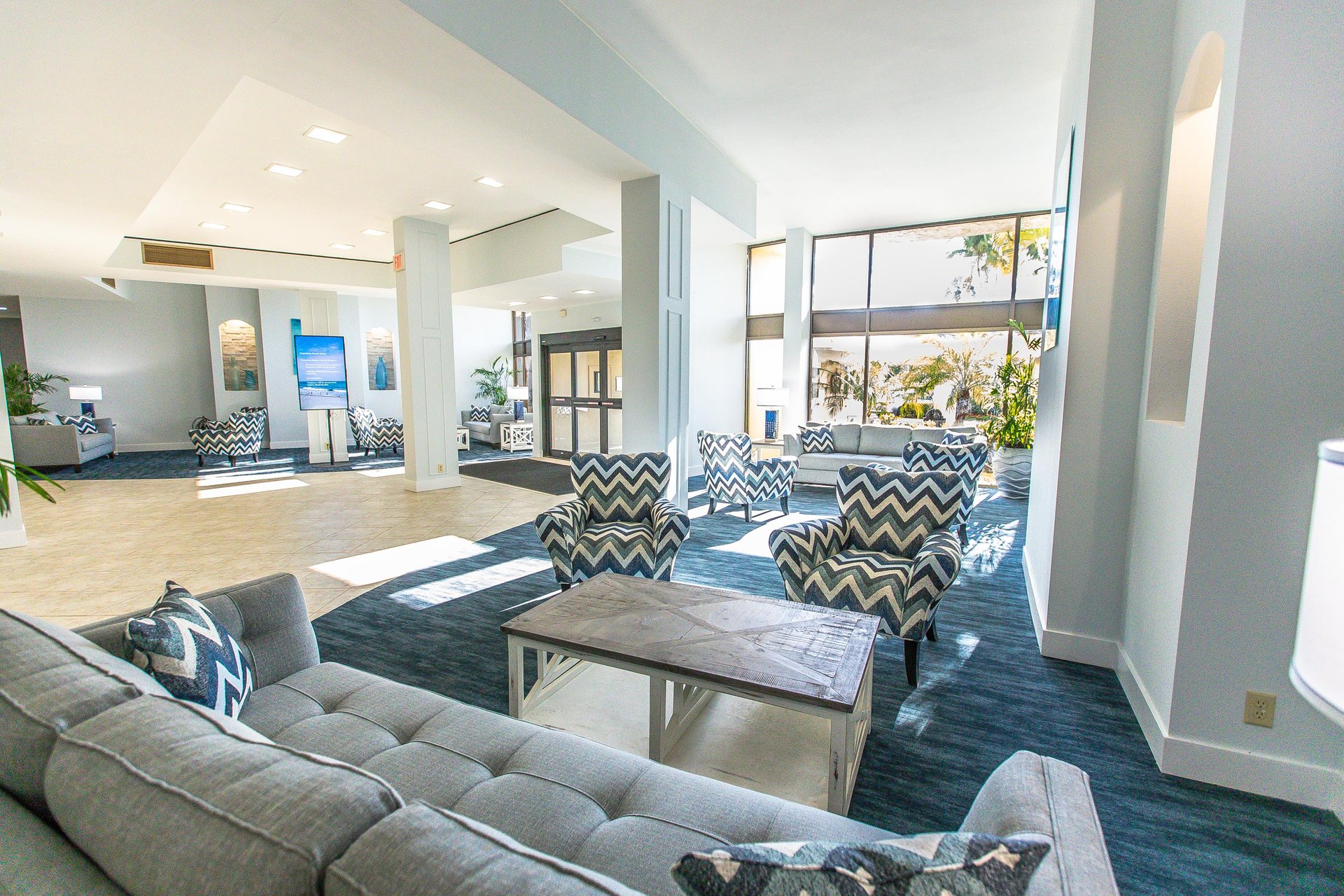 Unwind in this bright, modern lobby where stylish chevron chairs and plush seating create your perfect relaxation spot.
