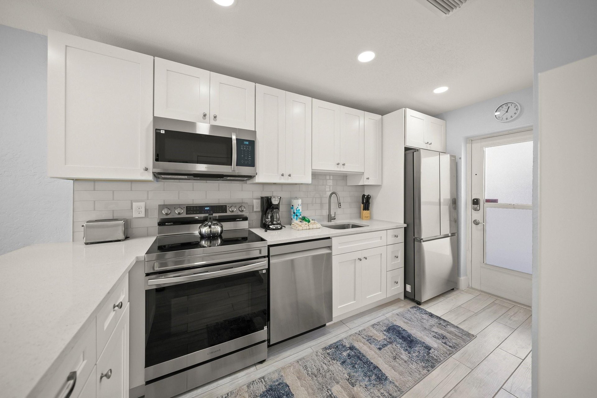 Your fully equipped kitchen features crisp white cabinets, stainless steel appliances, and clean countertops—perfect for preparing homecooked meals during your stay.