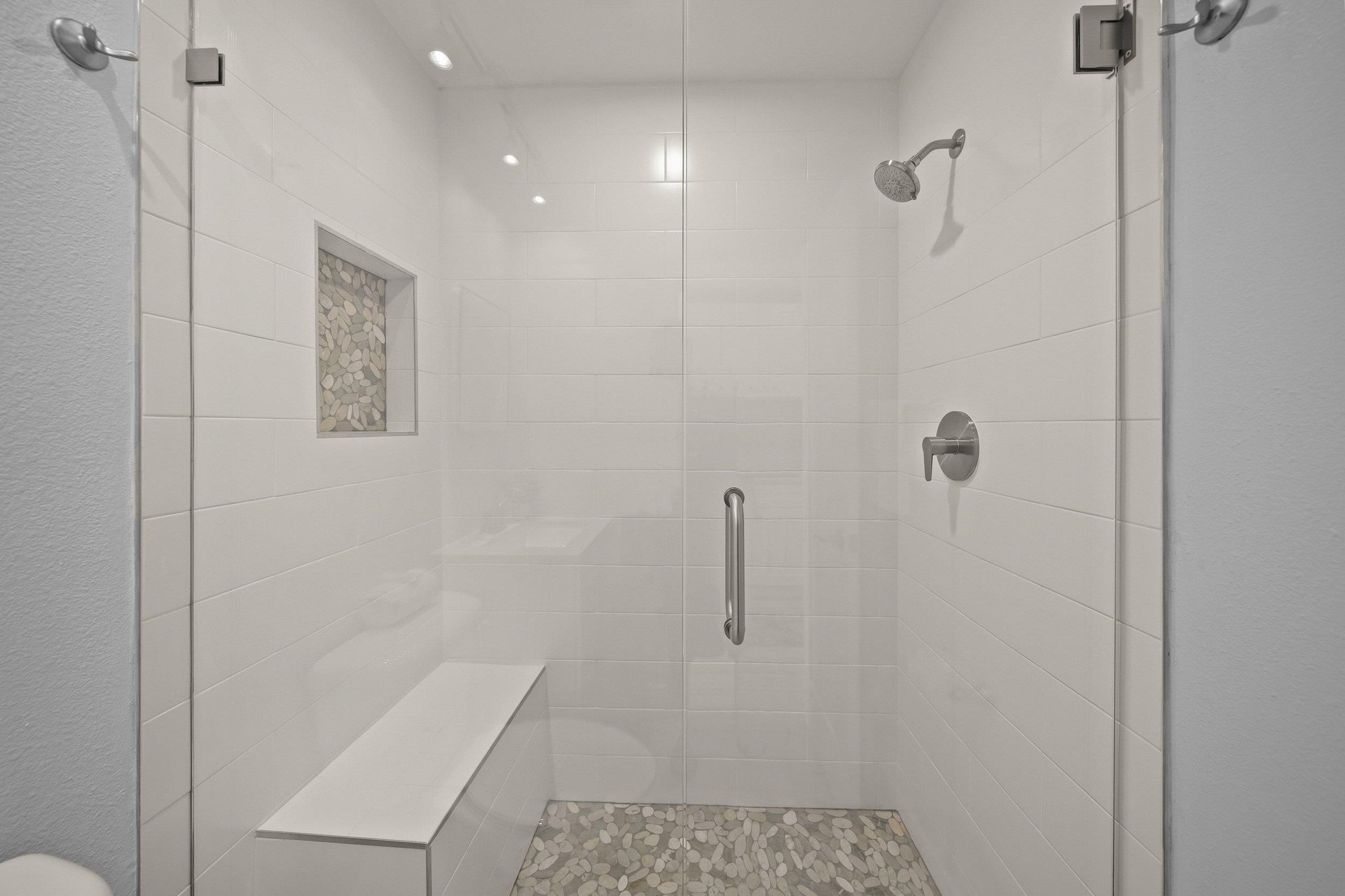 Step into your spacious glassenclosed shower with modern fixtures, stone accents, and thoughtful builtin seating for ultimate comfort.