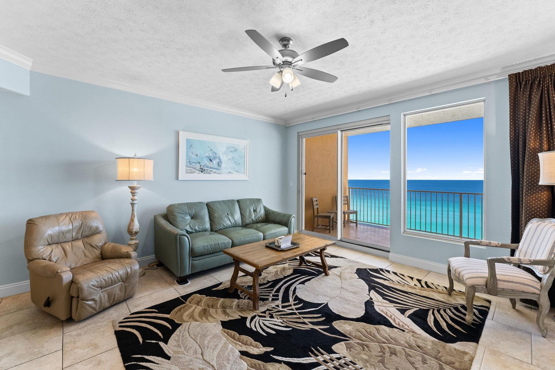 The living room offers ample, comfortable seating, including a leather recliner, a large television, and incredible gulf views.