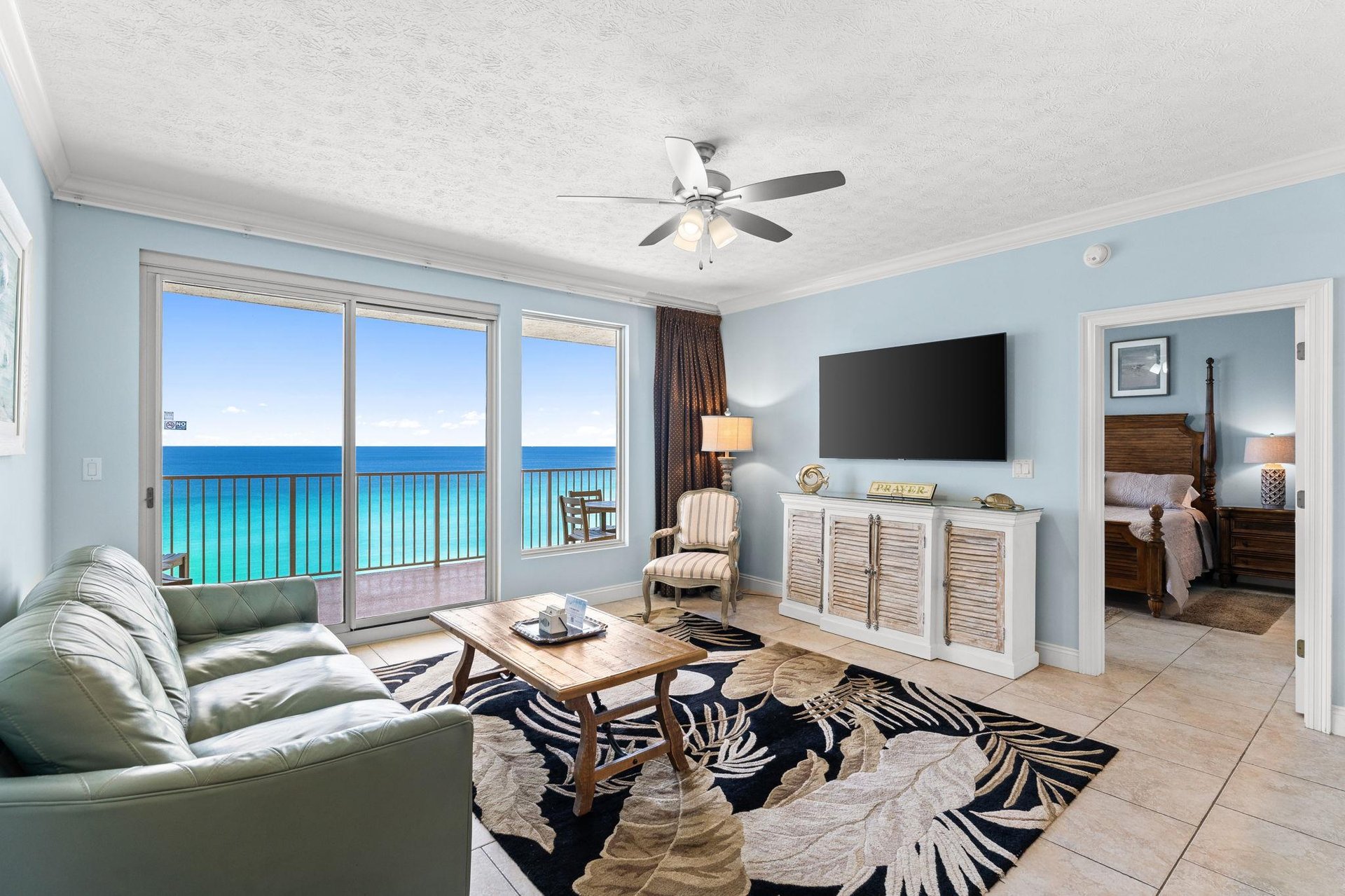 The living room offers ample, comfortable seating, including a leather recliner, a large television, and incredible gulf views.