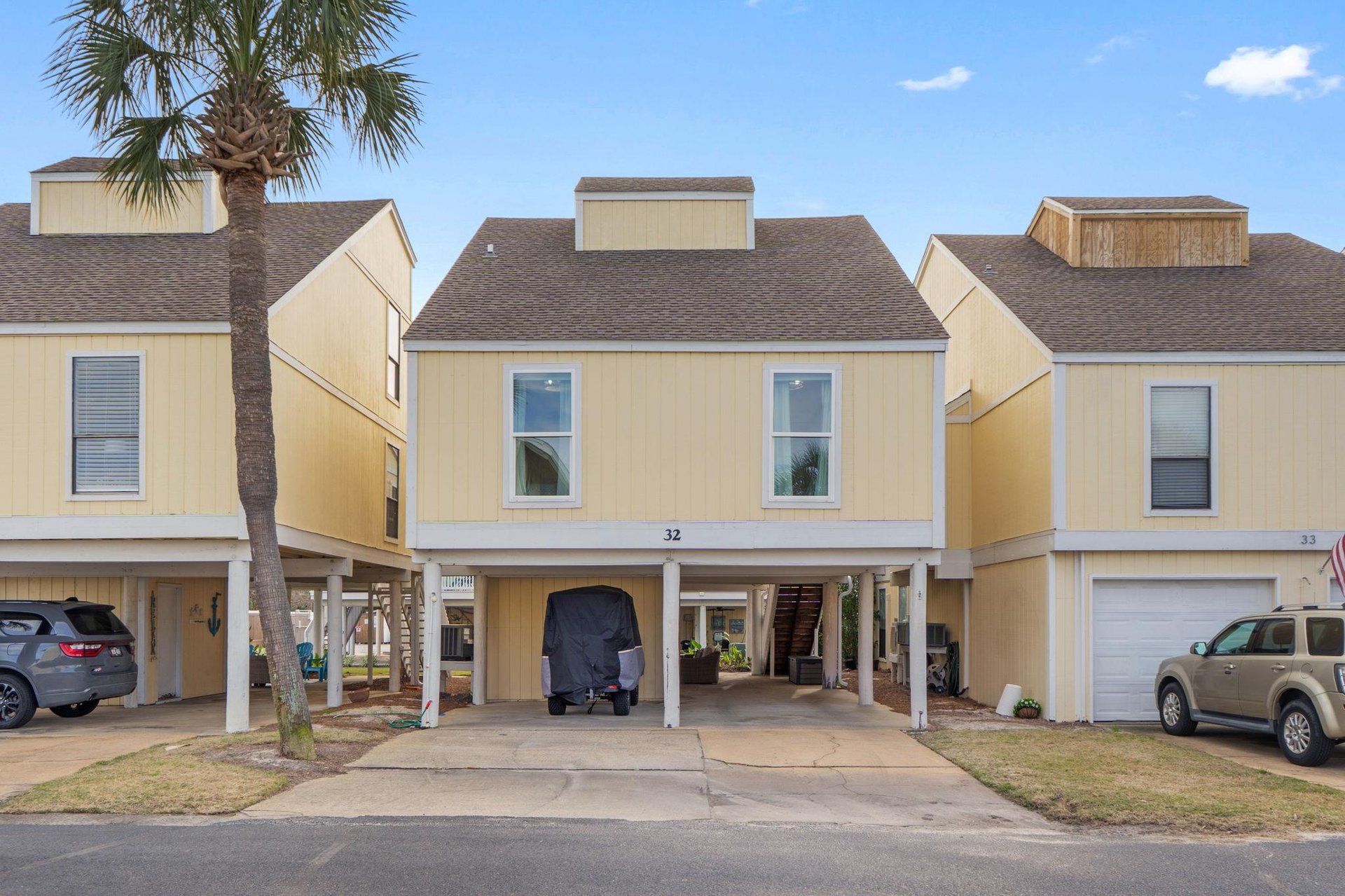 Beachstyle townhome with covered parking and palm tree, perfect for coastal getaways in this quiet residential community.