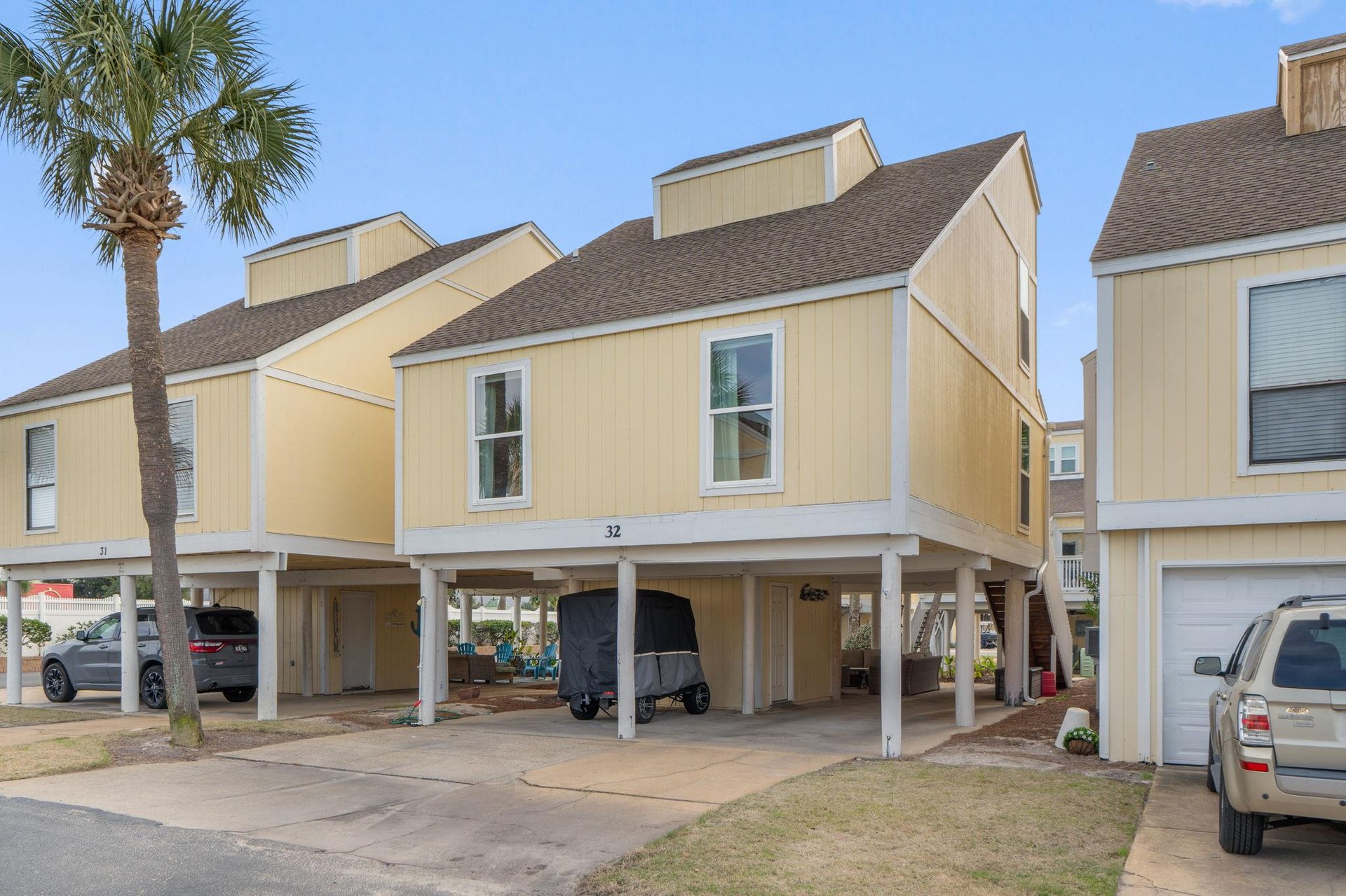 Coastal vacation rental with covered parking and tropical palm tree in a quiet residential community.