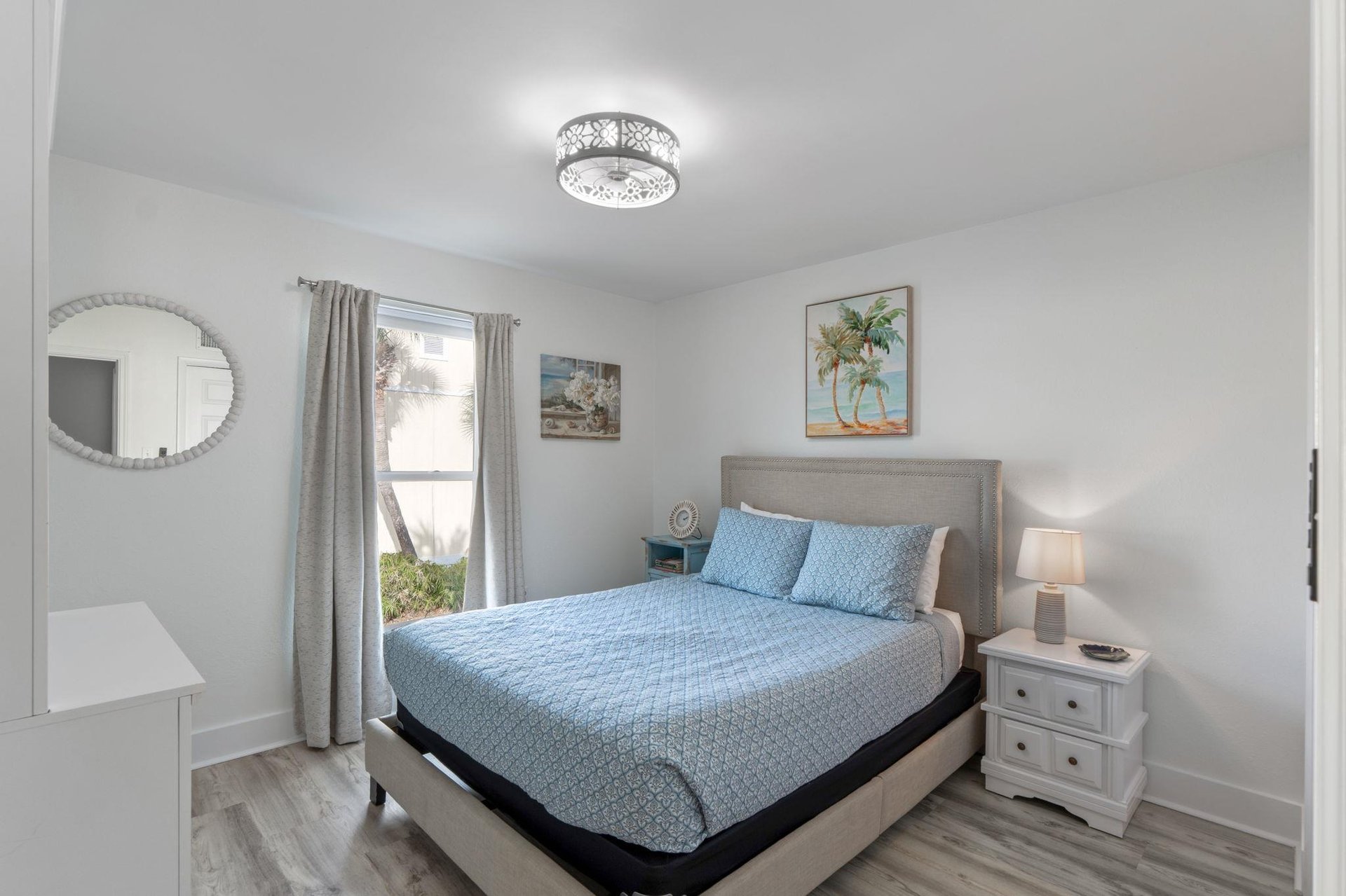 Drift off to peaceful sleep in your coastalthemed bedroom, where soft blue linens and tropical artwork create a serene escape.