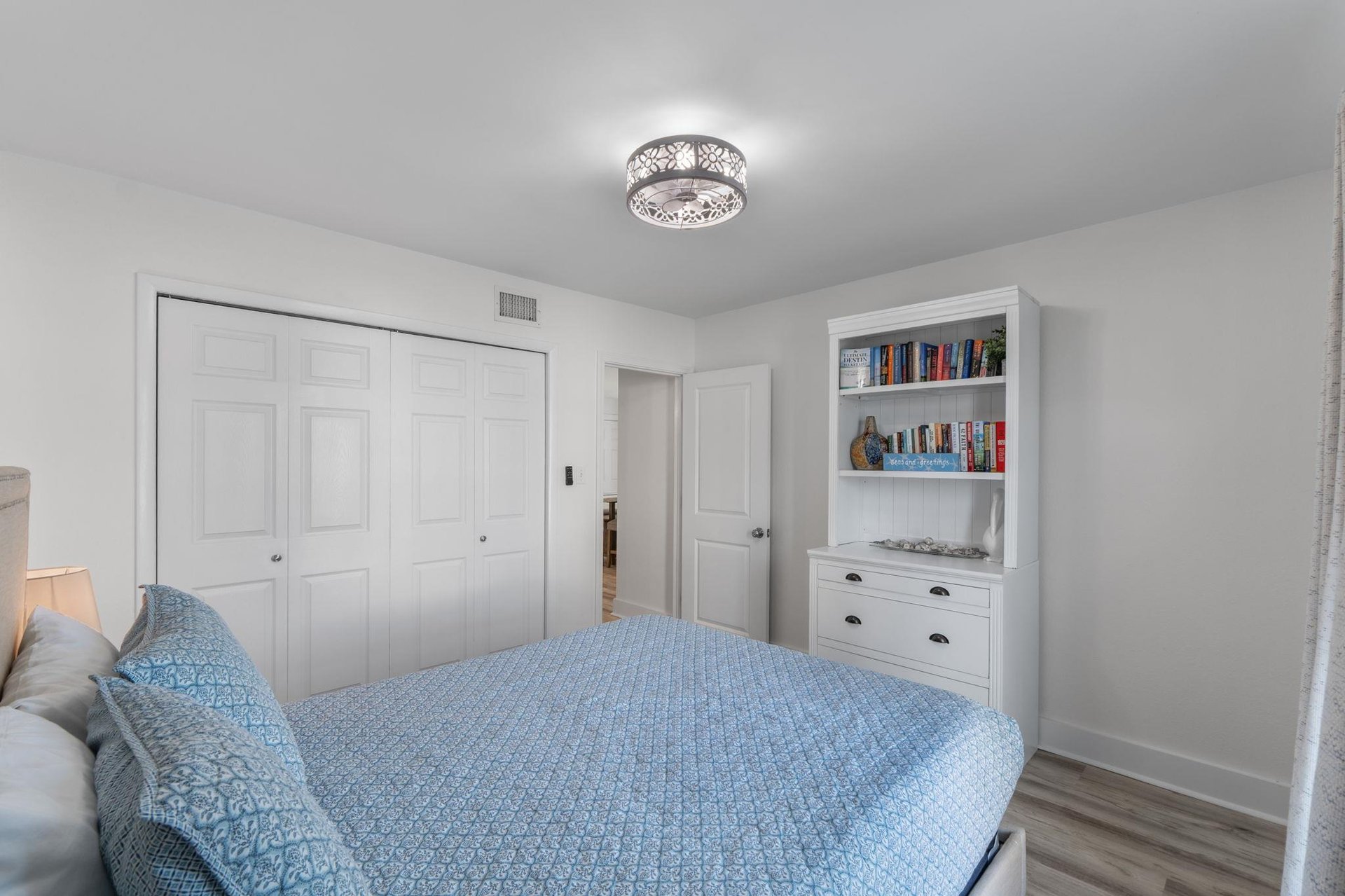 Unwind in your peaceful bedroom featuring a plush blue bed, builtin bookshelf filled with reads, and elegant lighting for restful nights.