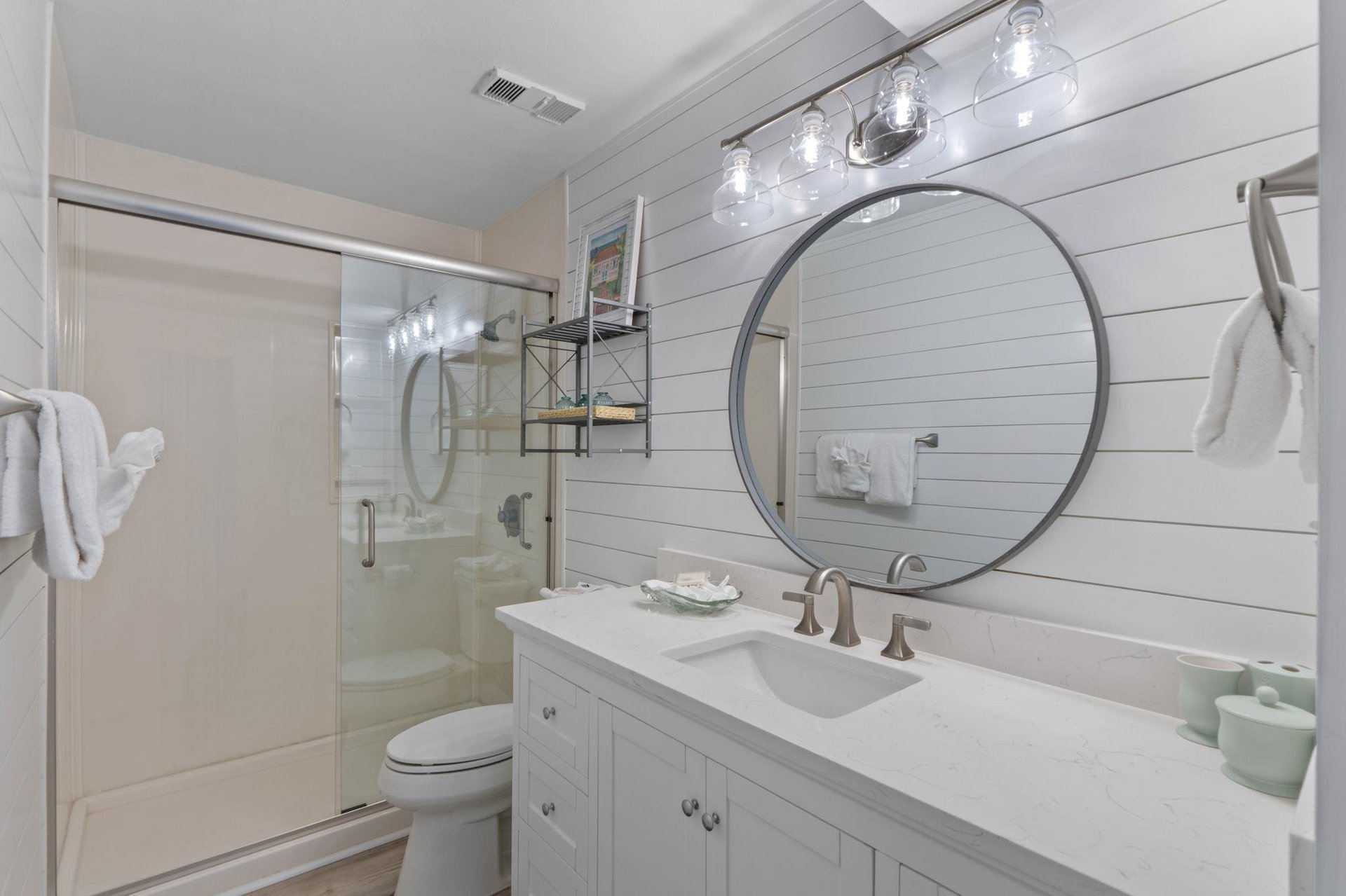 Refresh in your bright bathroom featuring a modern glass shower, elegant vanity, and coastalinspired shiplap walls.