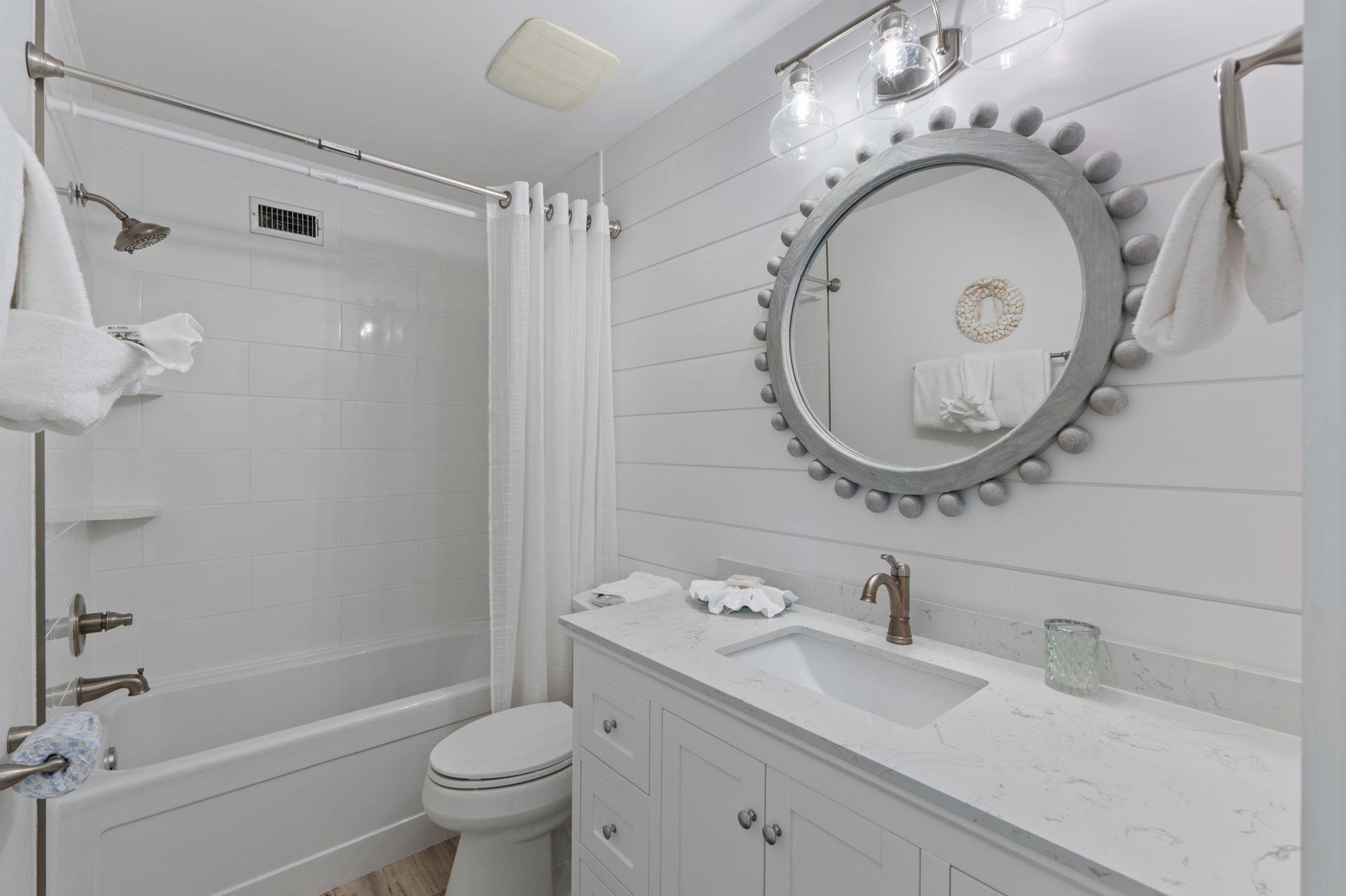 Step into this bright, coastalinspired bathroom featuring marble countertops, elegant shiplap walls, and all the amenities you need for your stay.