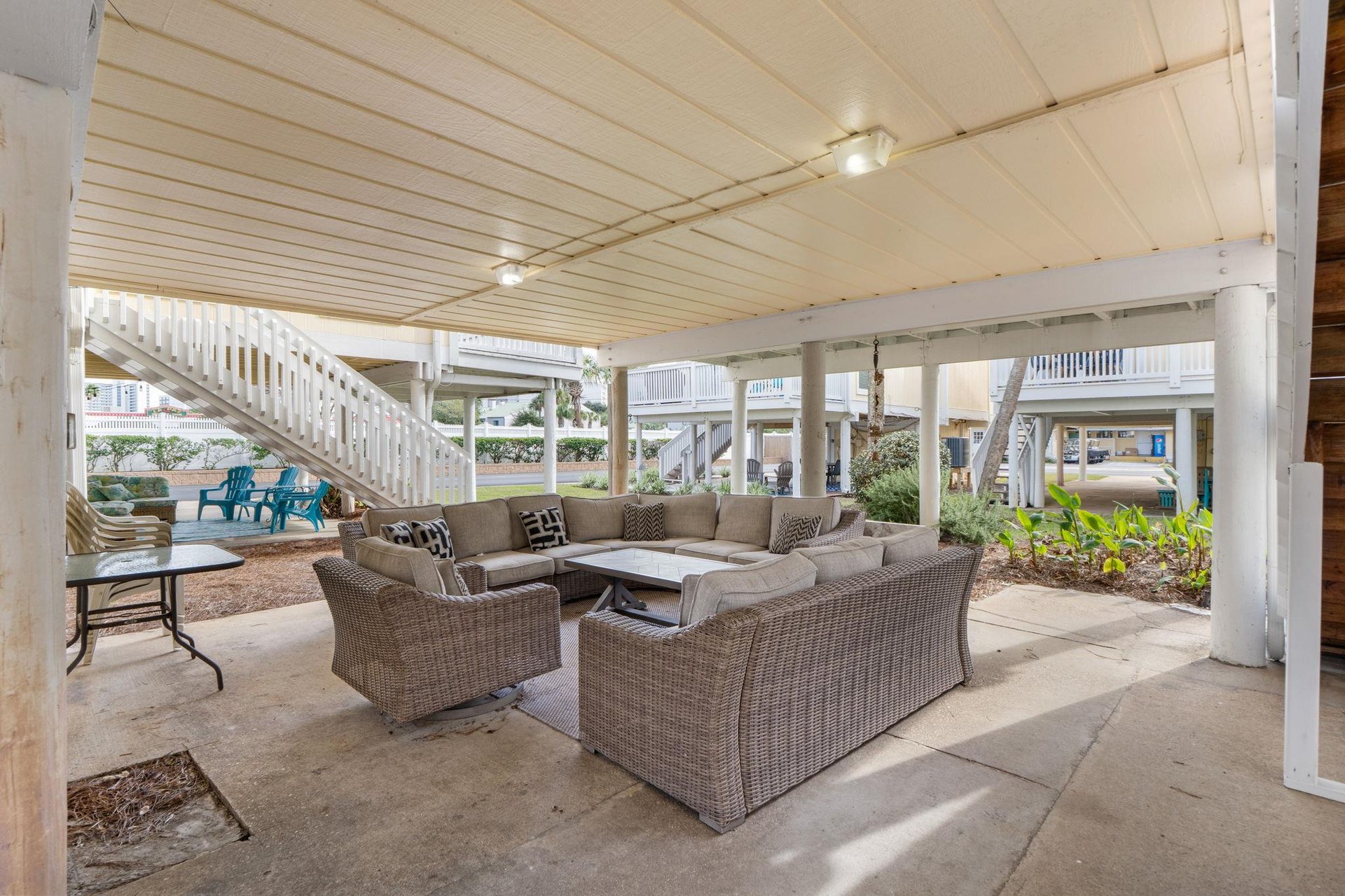 Your expansive covered outdoor living room invites relaxation with plush sectional seating and a central coffee table, perfect for unwinding after beach days.