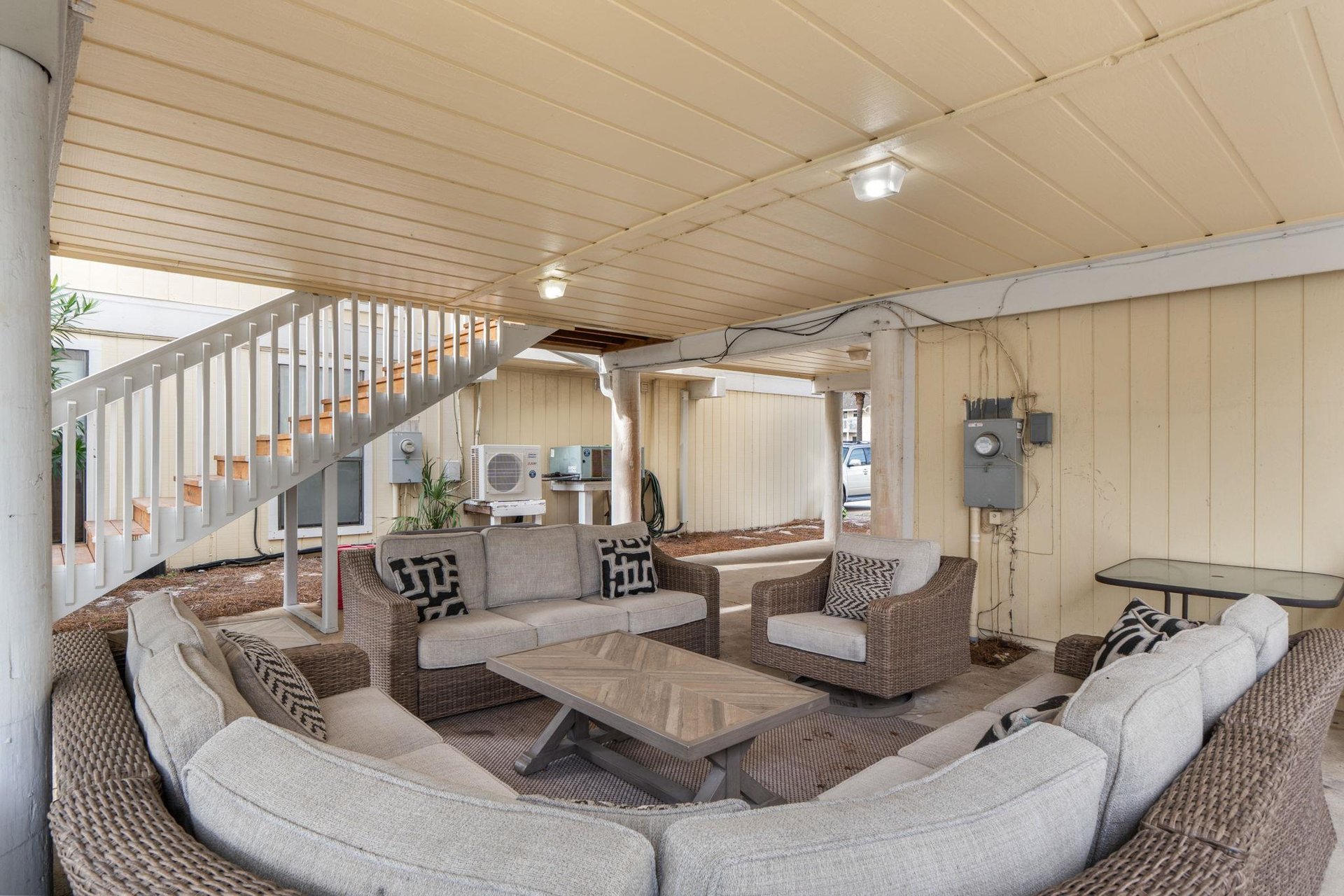Relax in your private covered patio featuring comfortable wicker seating, perfect for morning coffee or evening conversations under soft lighting.