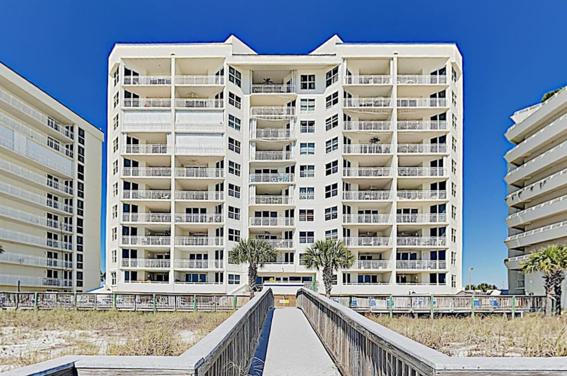 View of the beachside exterior of SeaSpray East with a wooden boardwalk leading to the Gulf