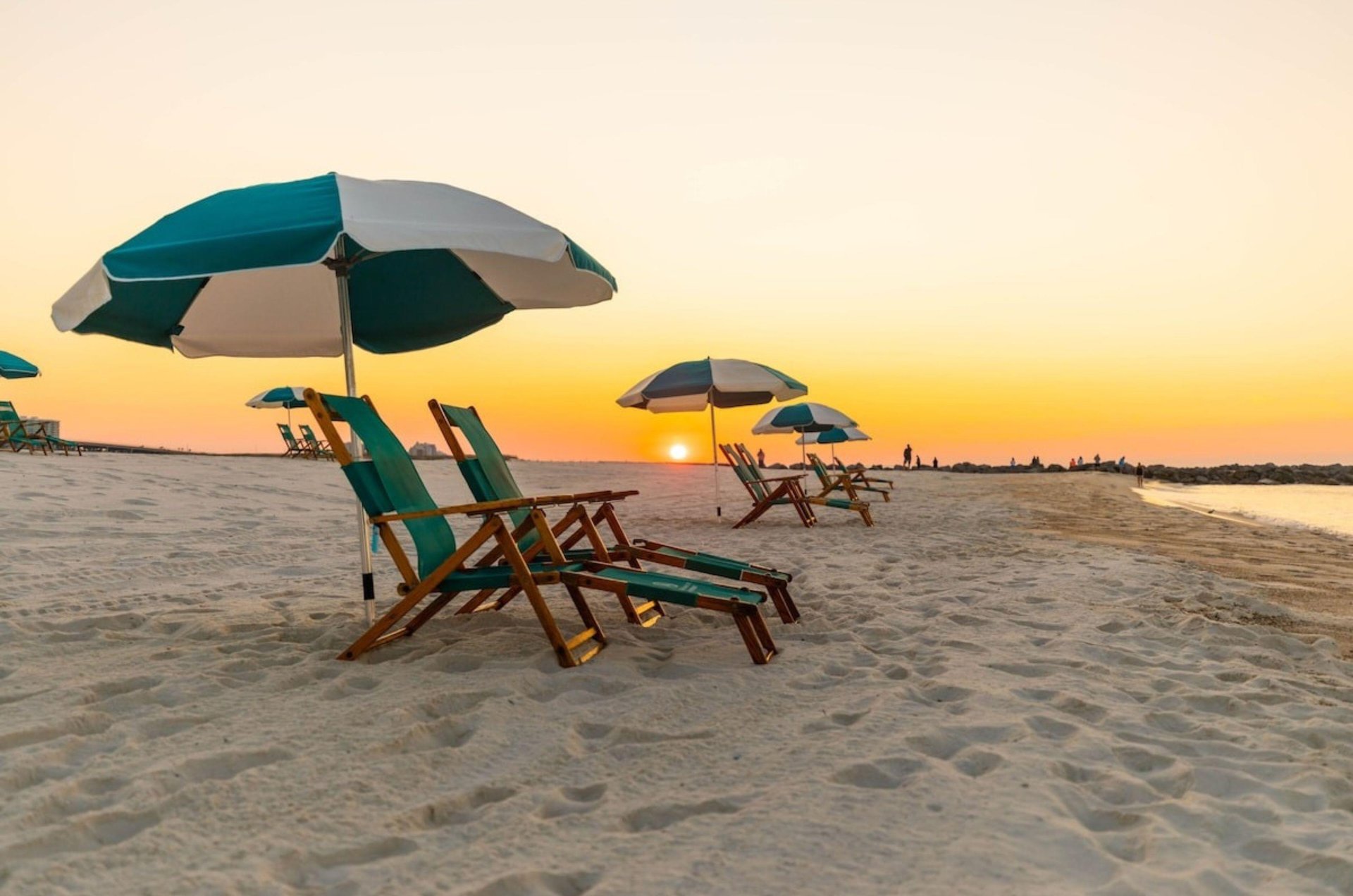 A lounge chair and beach umbrella on the beach at sunset at Perdido Beach Resort