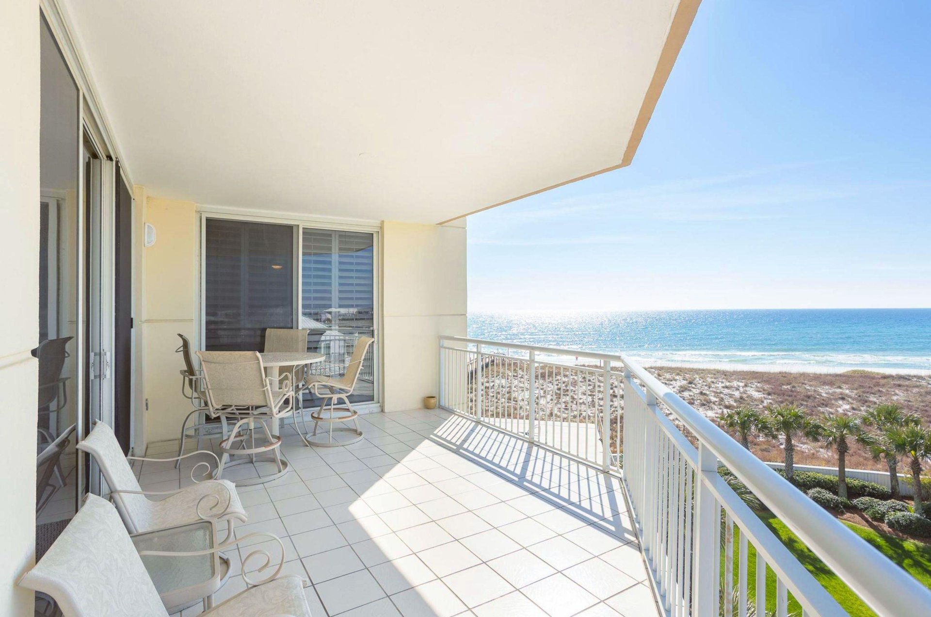 A private balcony with chairs and a dining table overlooking the beach